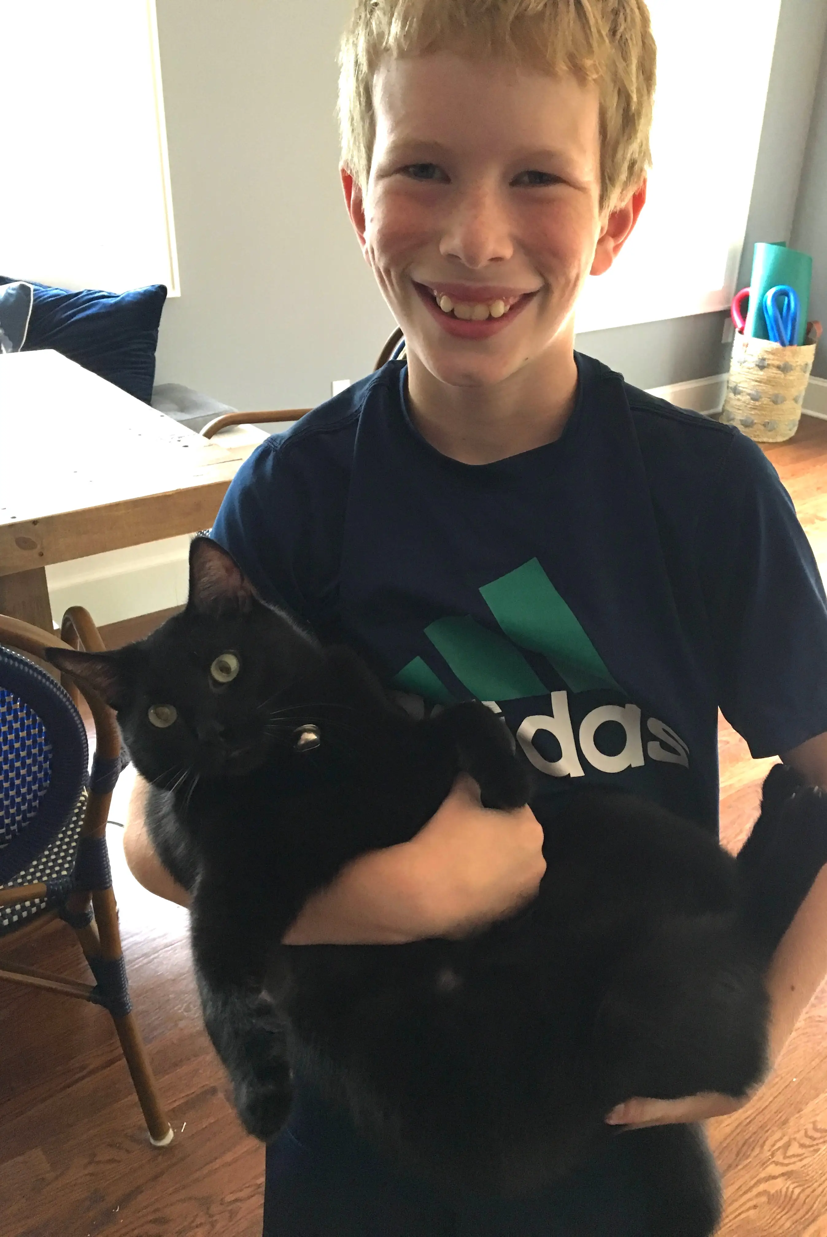 The author's son poses with a black cat.