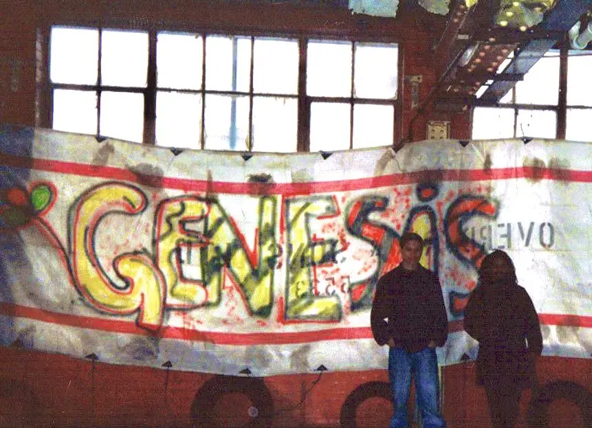 Two people standing in a warehouse with giant sign 