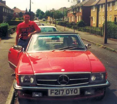 A man standing next to a red race car.