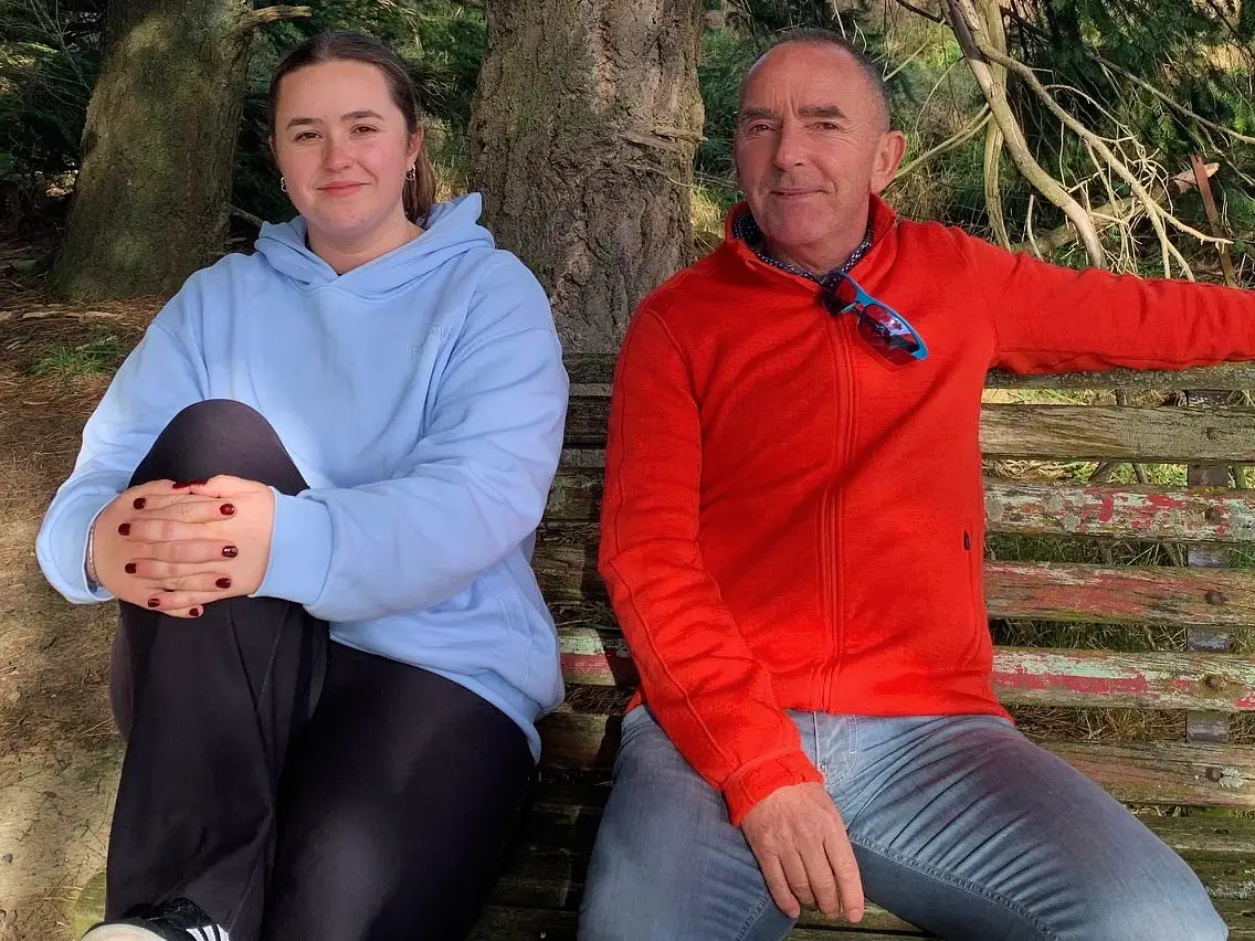 Mick Jensen and his college-aged daughter sitting on a bench