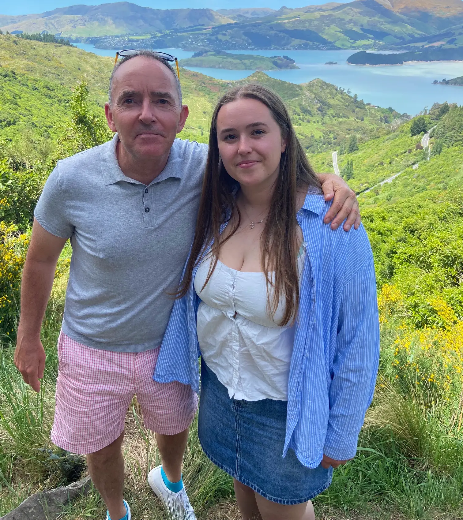Mick Jensen and his college-aged daughter in front of a green and water landscape