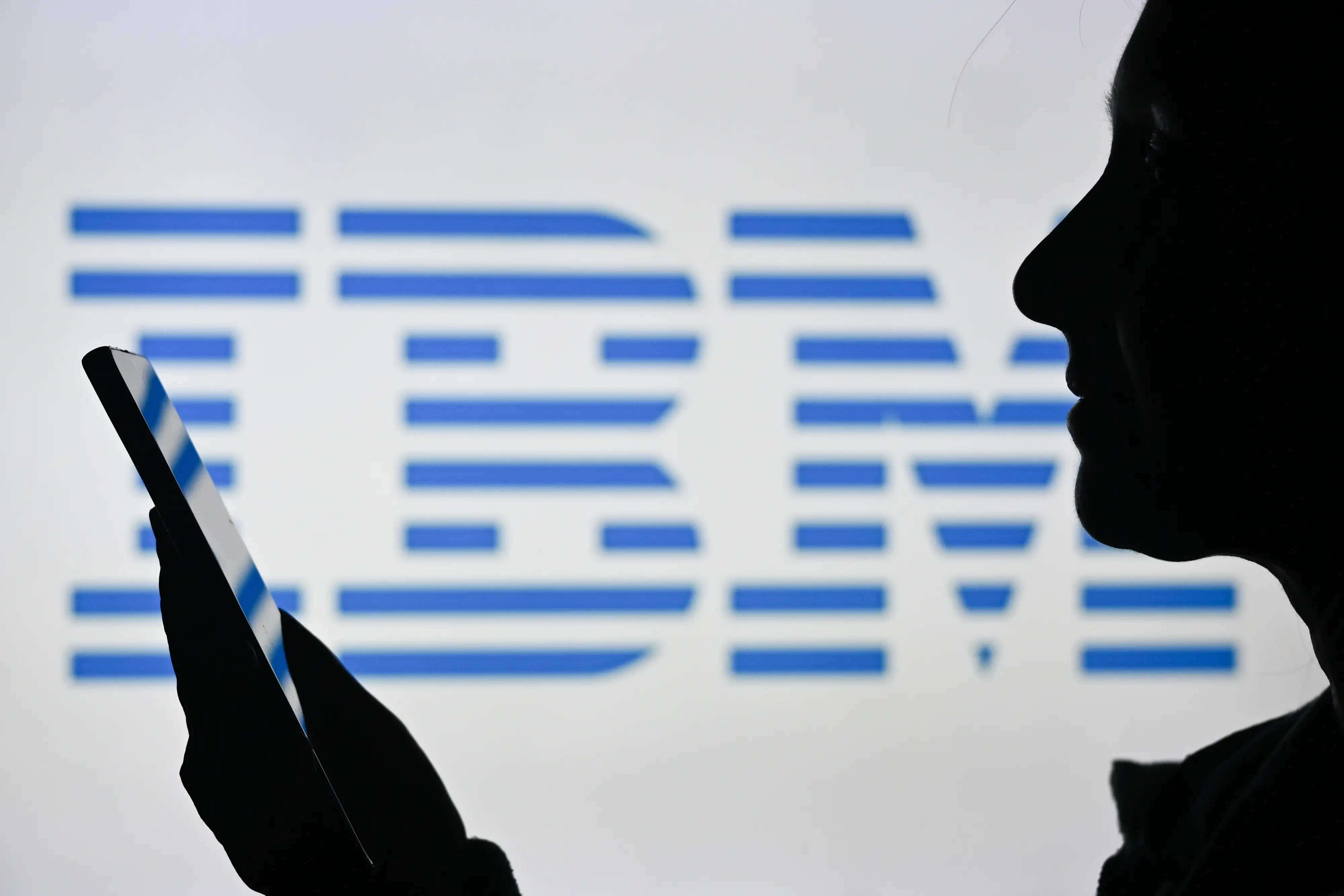 Photo of a person holding up their iphone in front of an IBM sign.