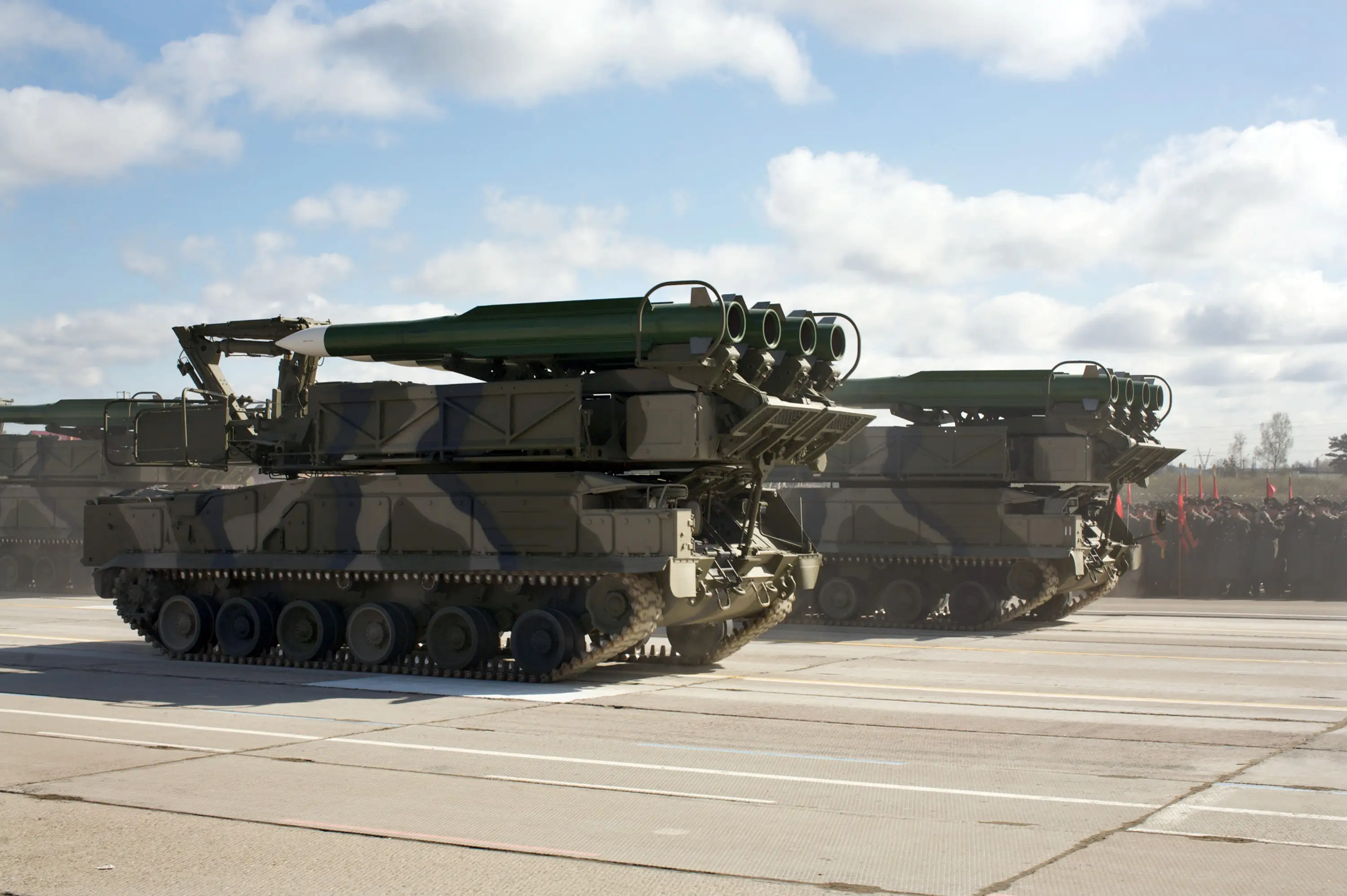Two large green camouflage vehicles on tracks, with weaponry on top