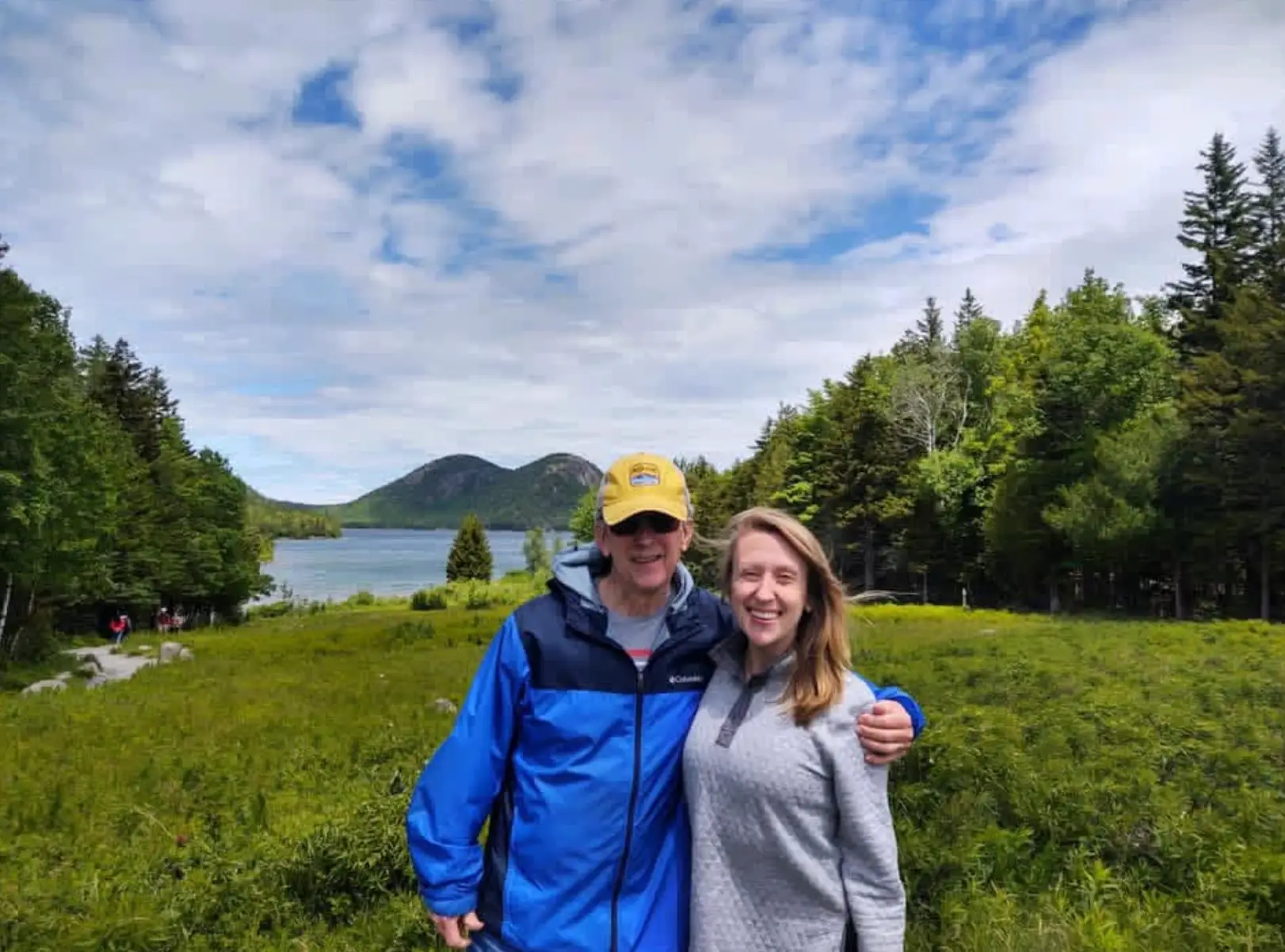The writer and her dad posing in front of the water at Acadia National Park in Maine.