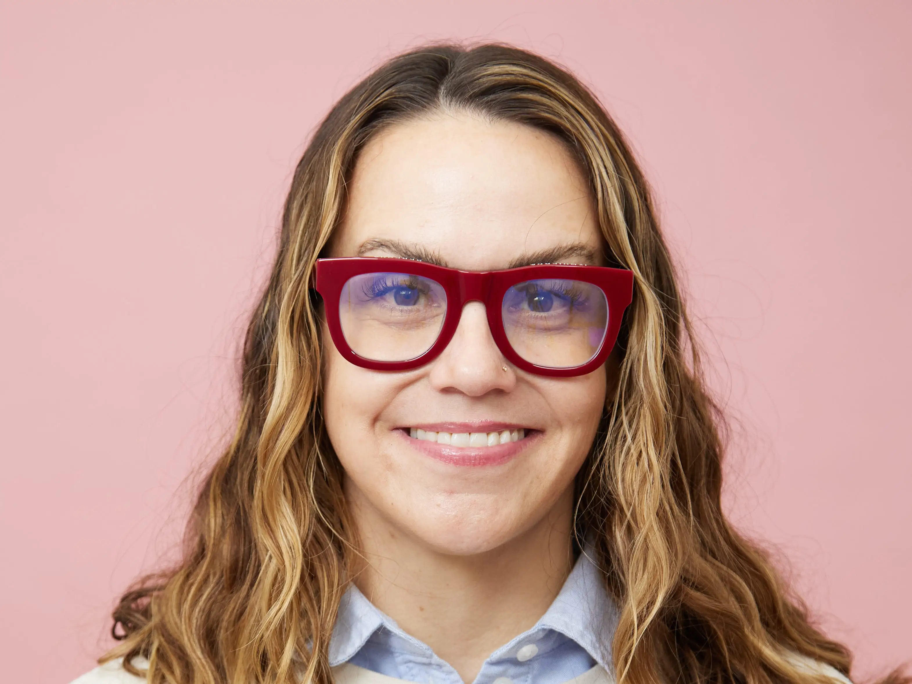 head shot of a woman in a New York sweatshirt and red glasses