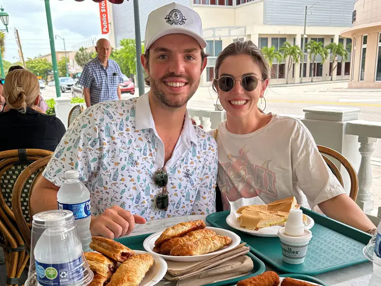 Taylor and her friend sit at an outdoor table with plates of pastries.