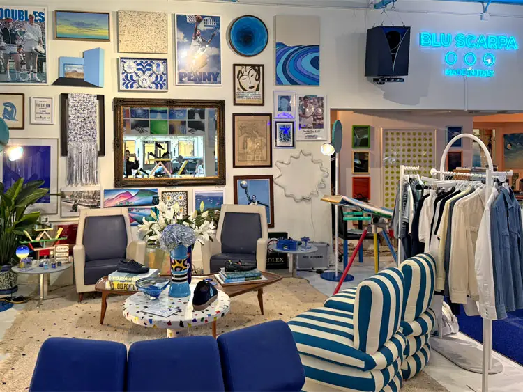 The interior of Blu Scarpa, a store with blue artwork on the walls, blue furniture, and racks of clothing.