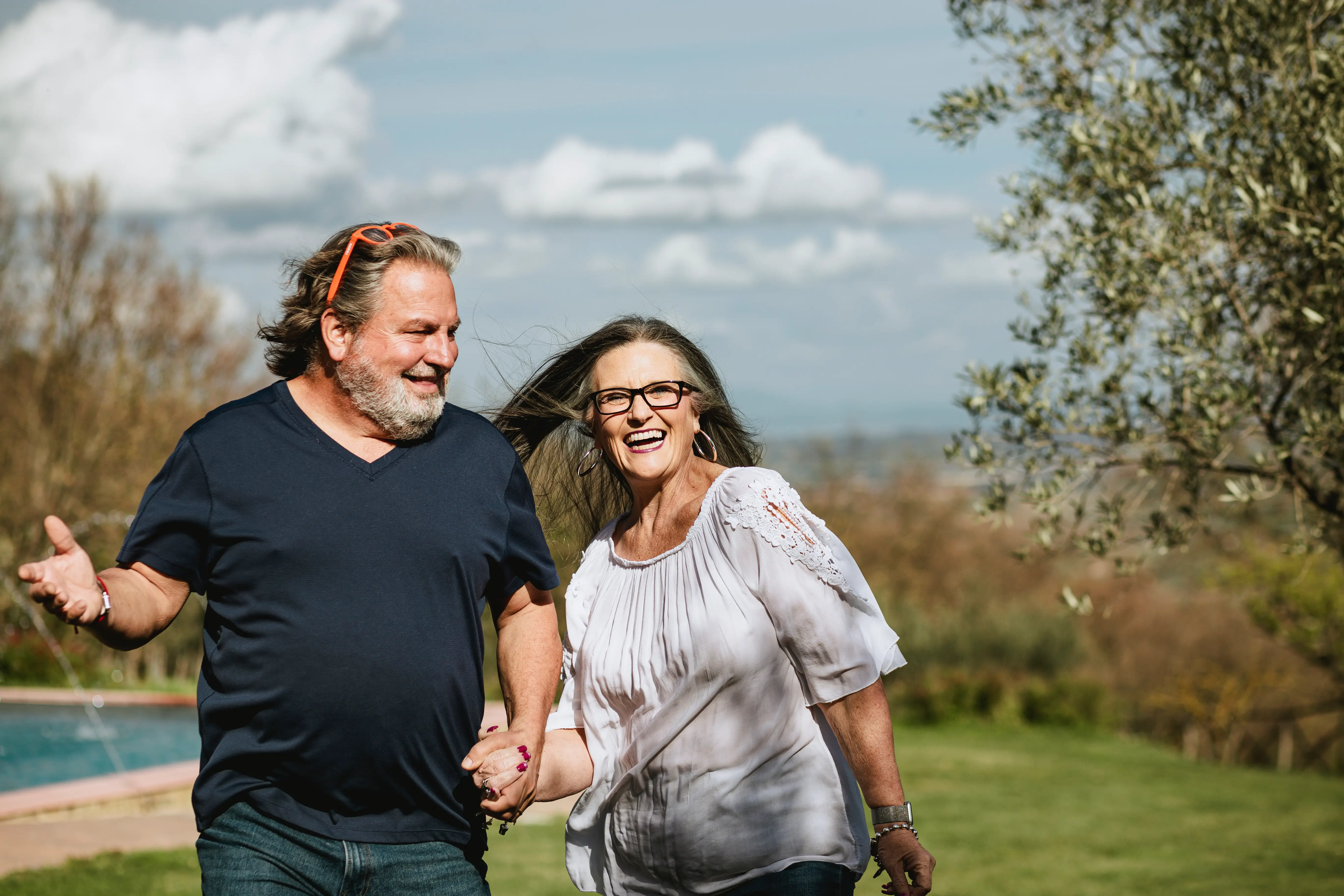 Husband and wife walking alongside pool in Tuscany.