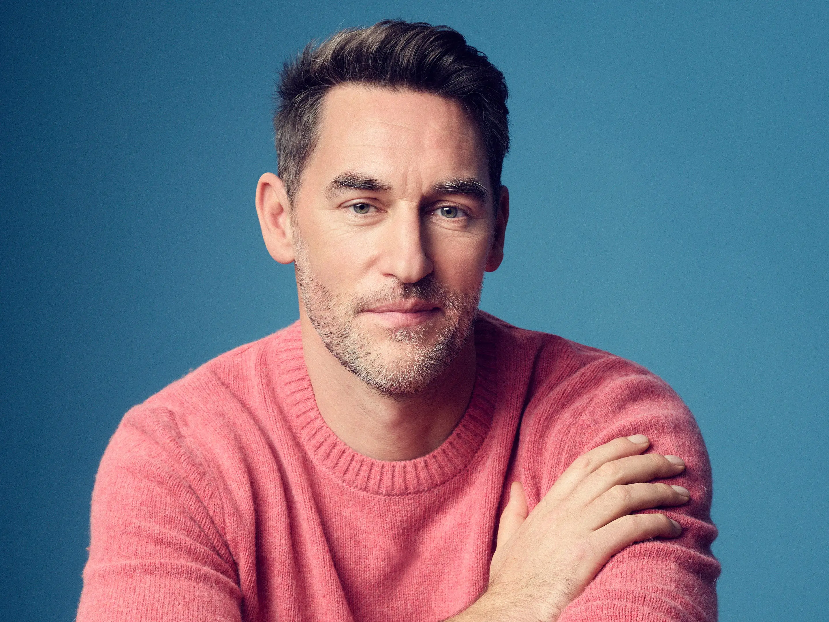 A man poses with ingredients on wooden chopping boards.