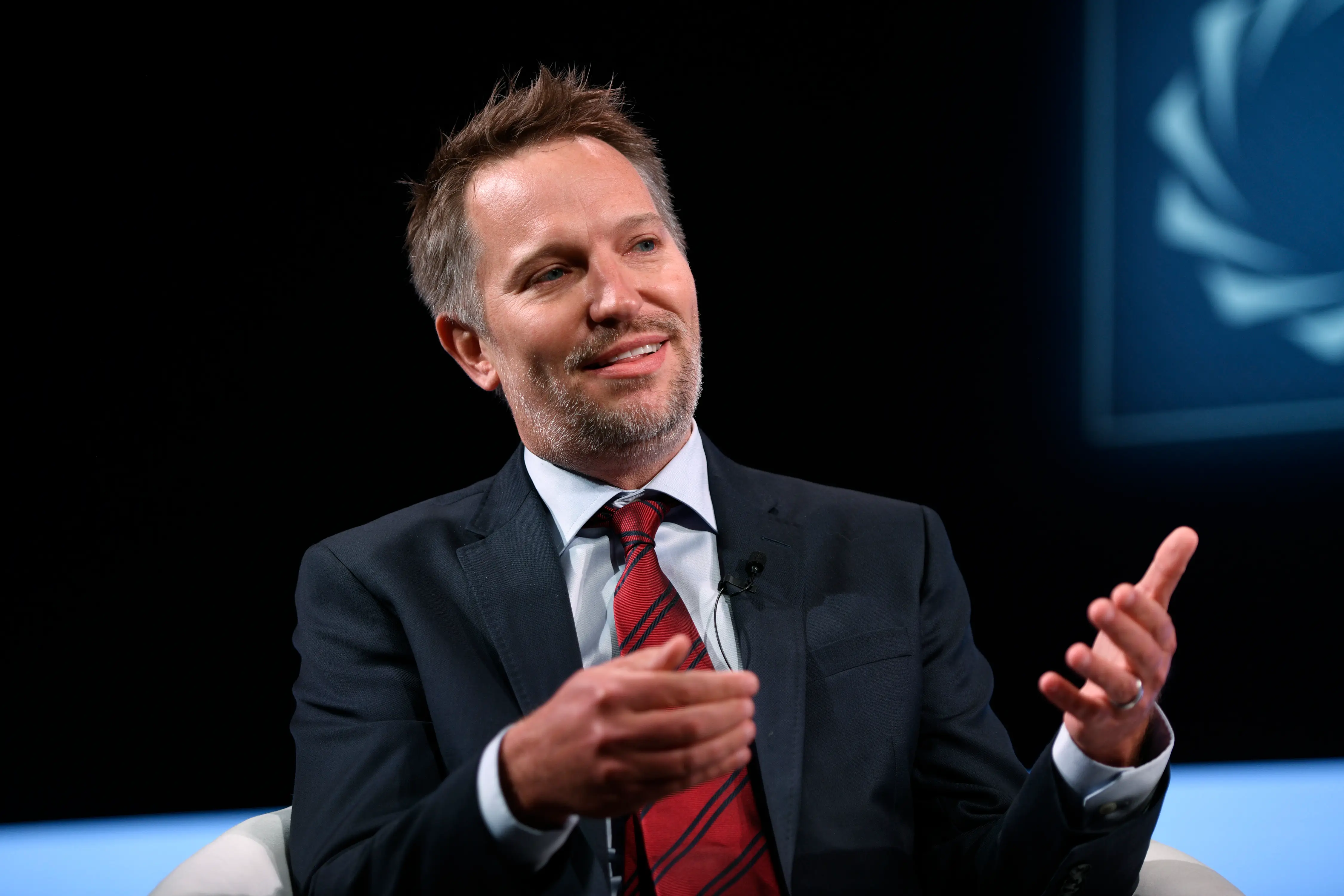 Ryan Roslansky, the CEO of LinkedIn, talks onstage in a gray suit with a red tie.
