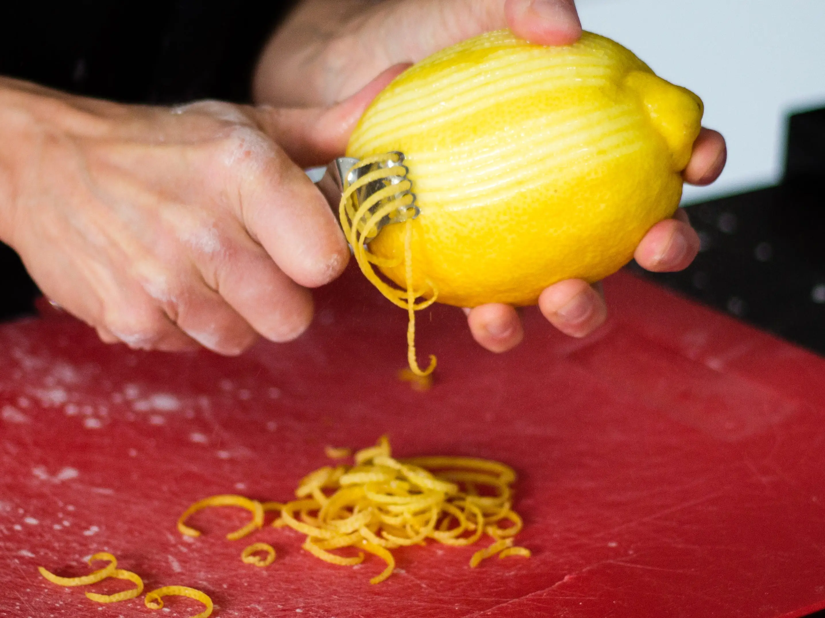 Person zesting lemon over cutting board