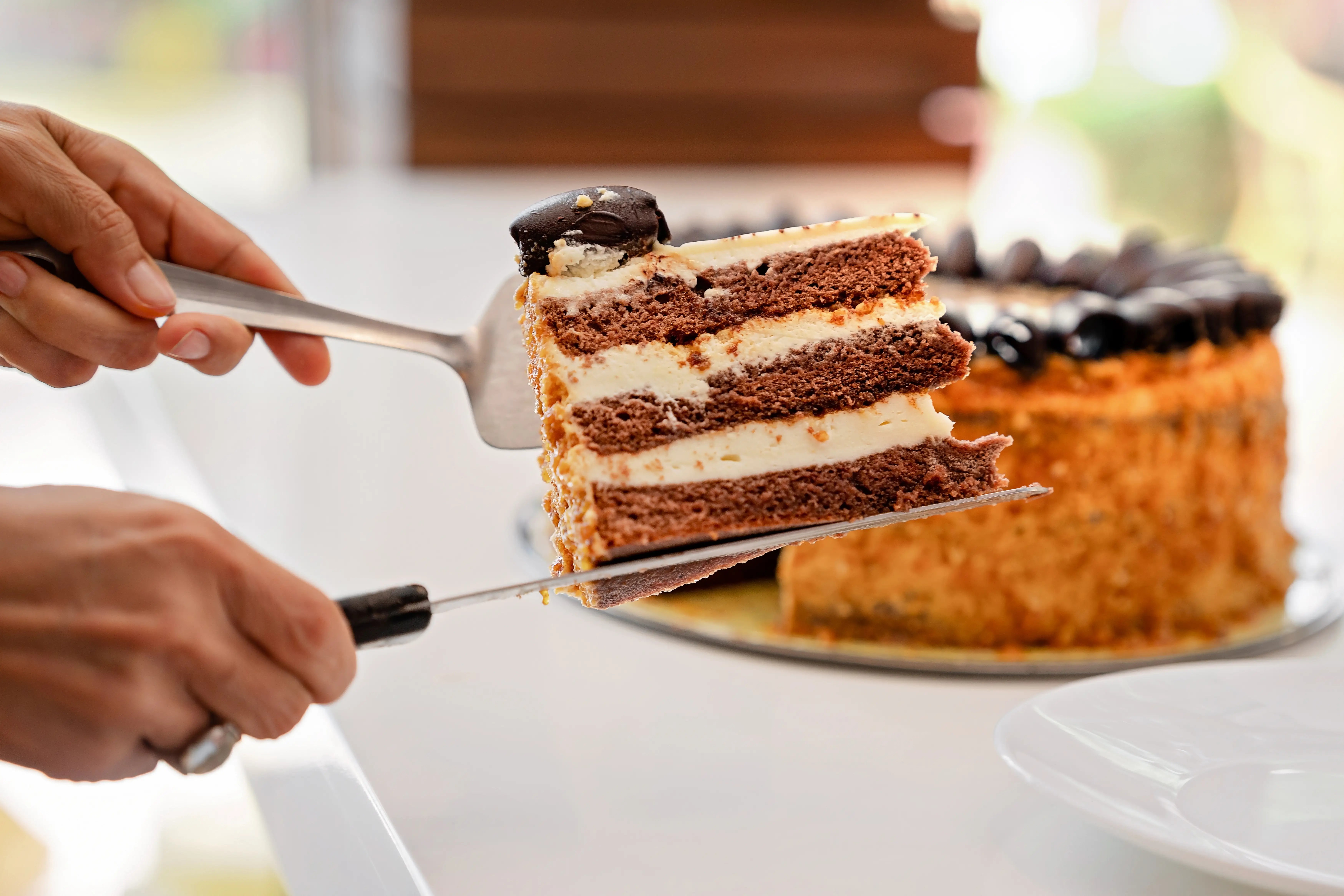 Close-up of a person taking a slice of a cake