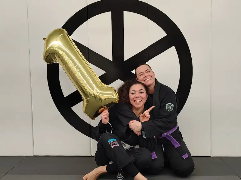 The writer posing with another person and a 1-year balloon at the Brazilian jiu-jitsu gym.