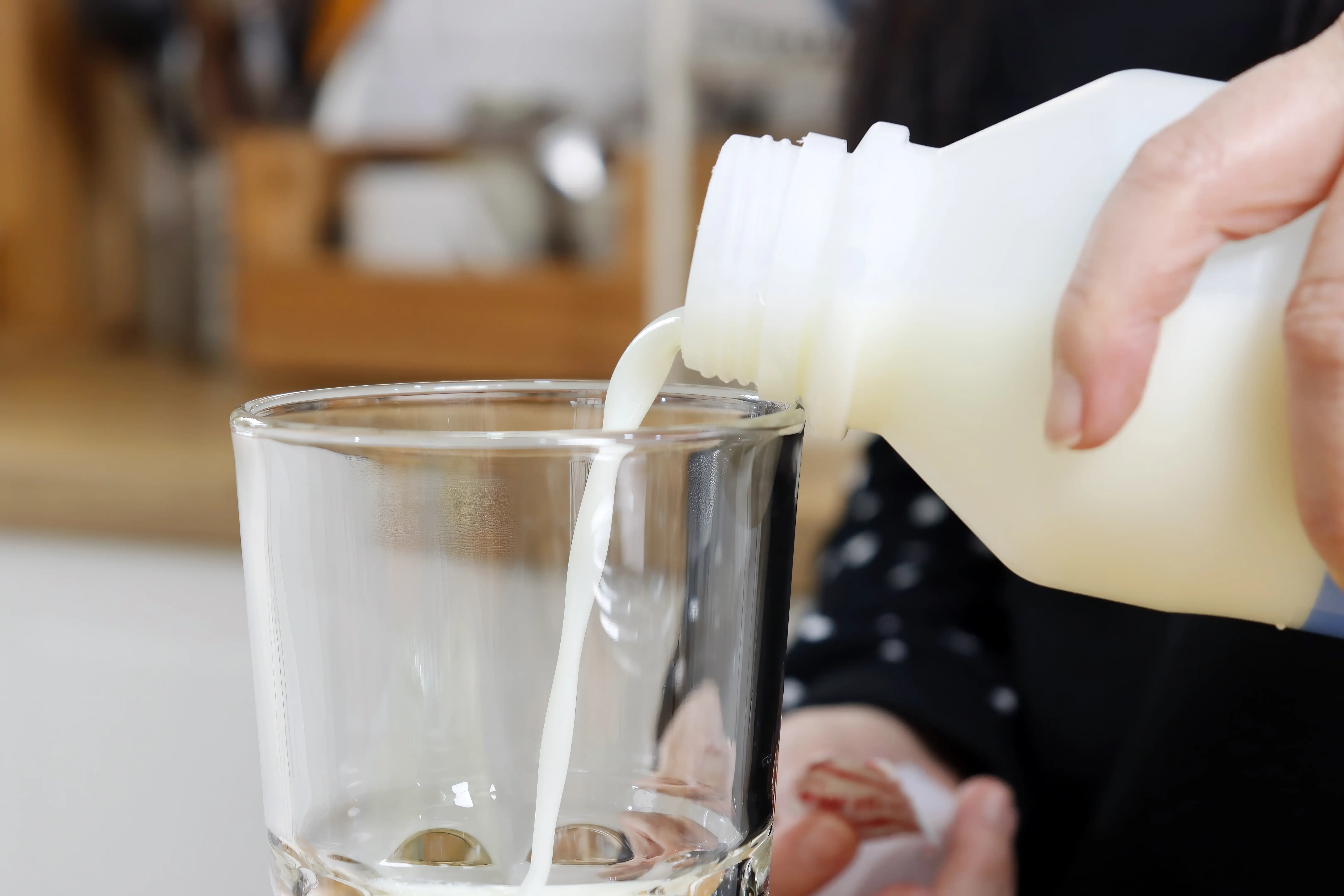 Person pouring milk into glass
