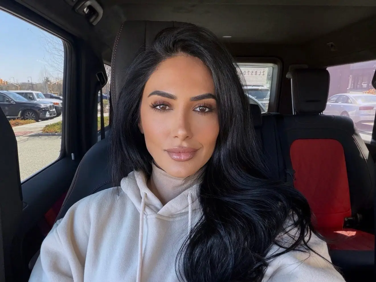A woman looking into the camera in a car.