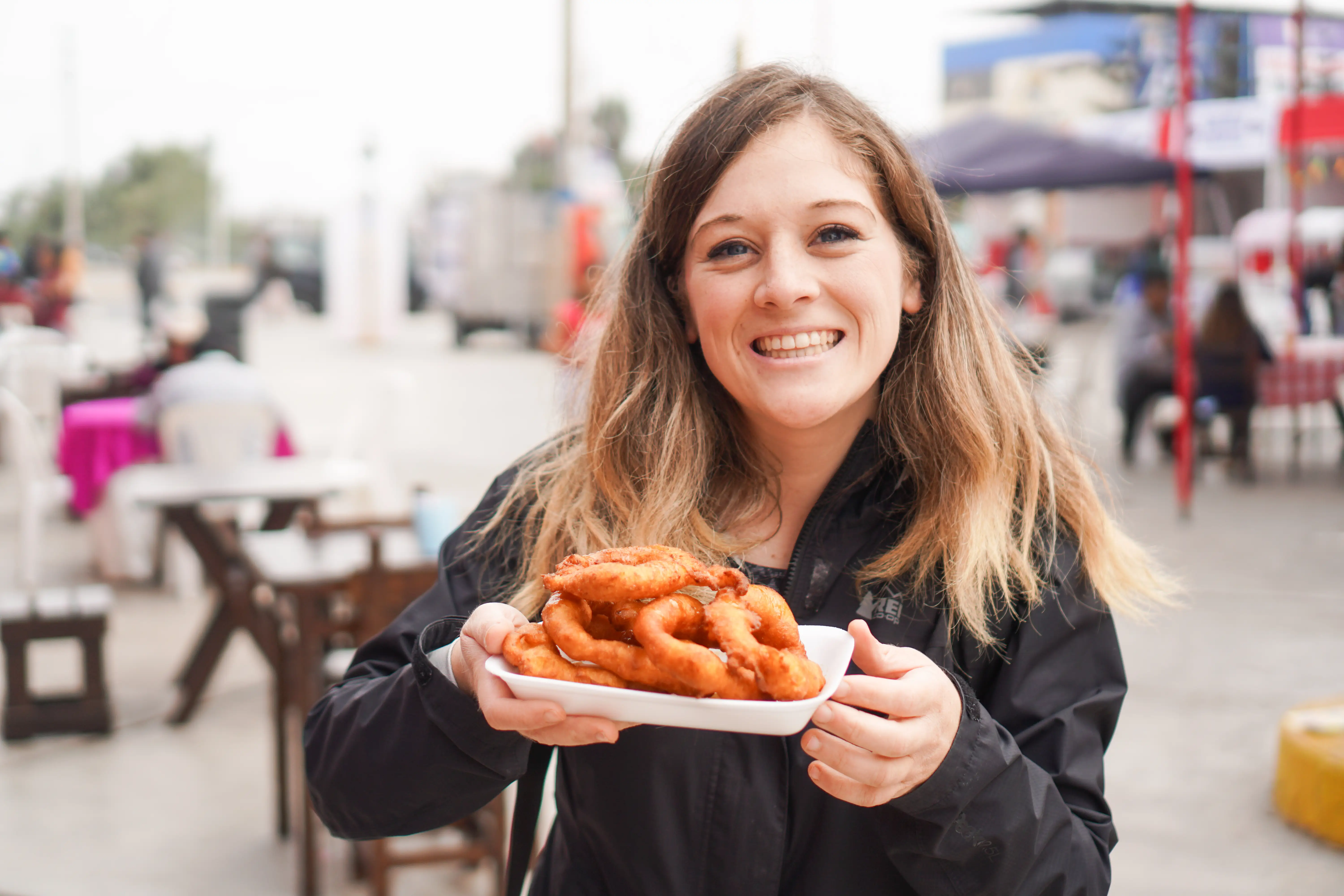Woman smiling holding plate of fried dough