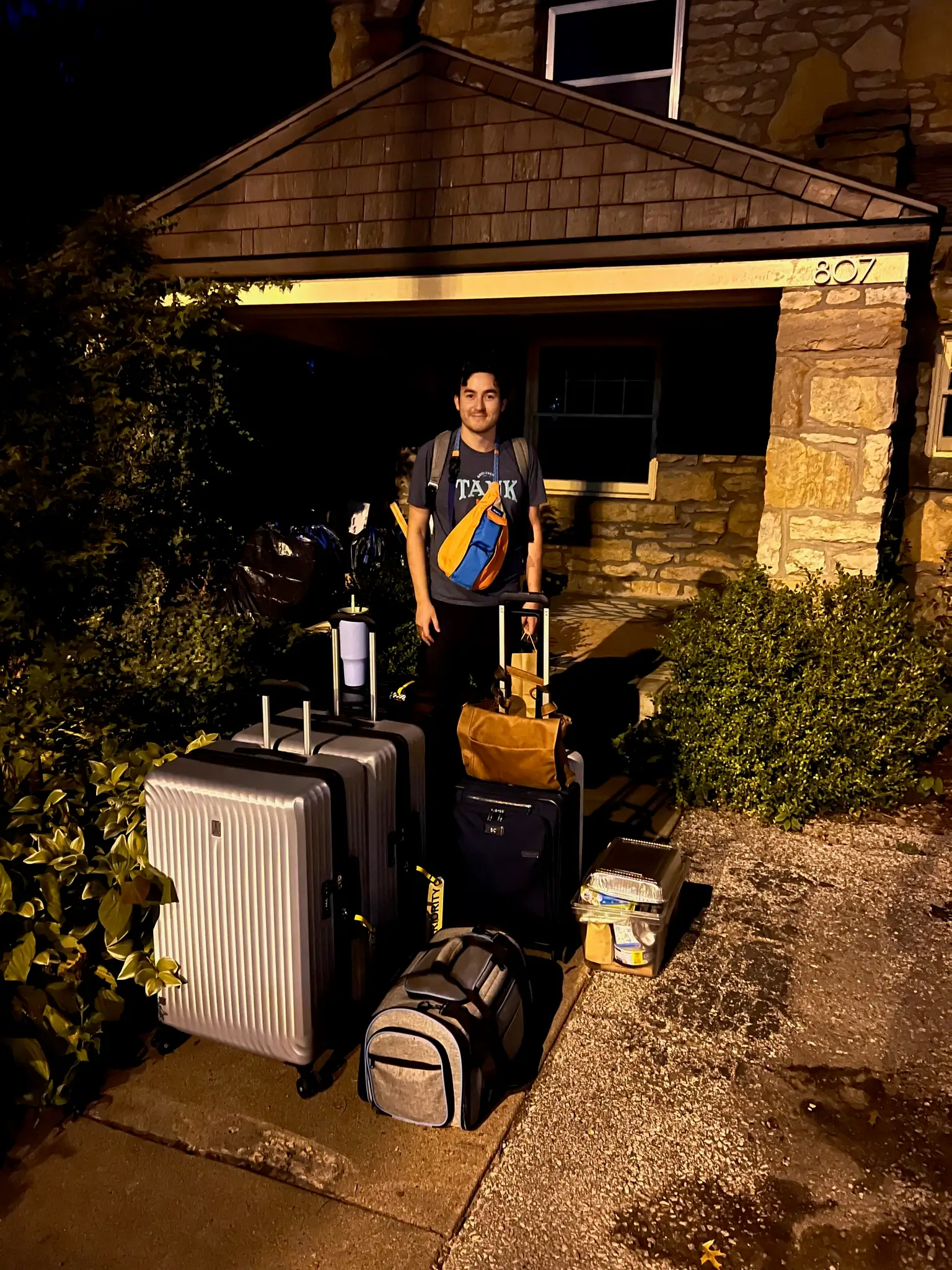 A man with a lot of luggage outside a home.