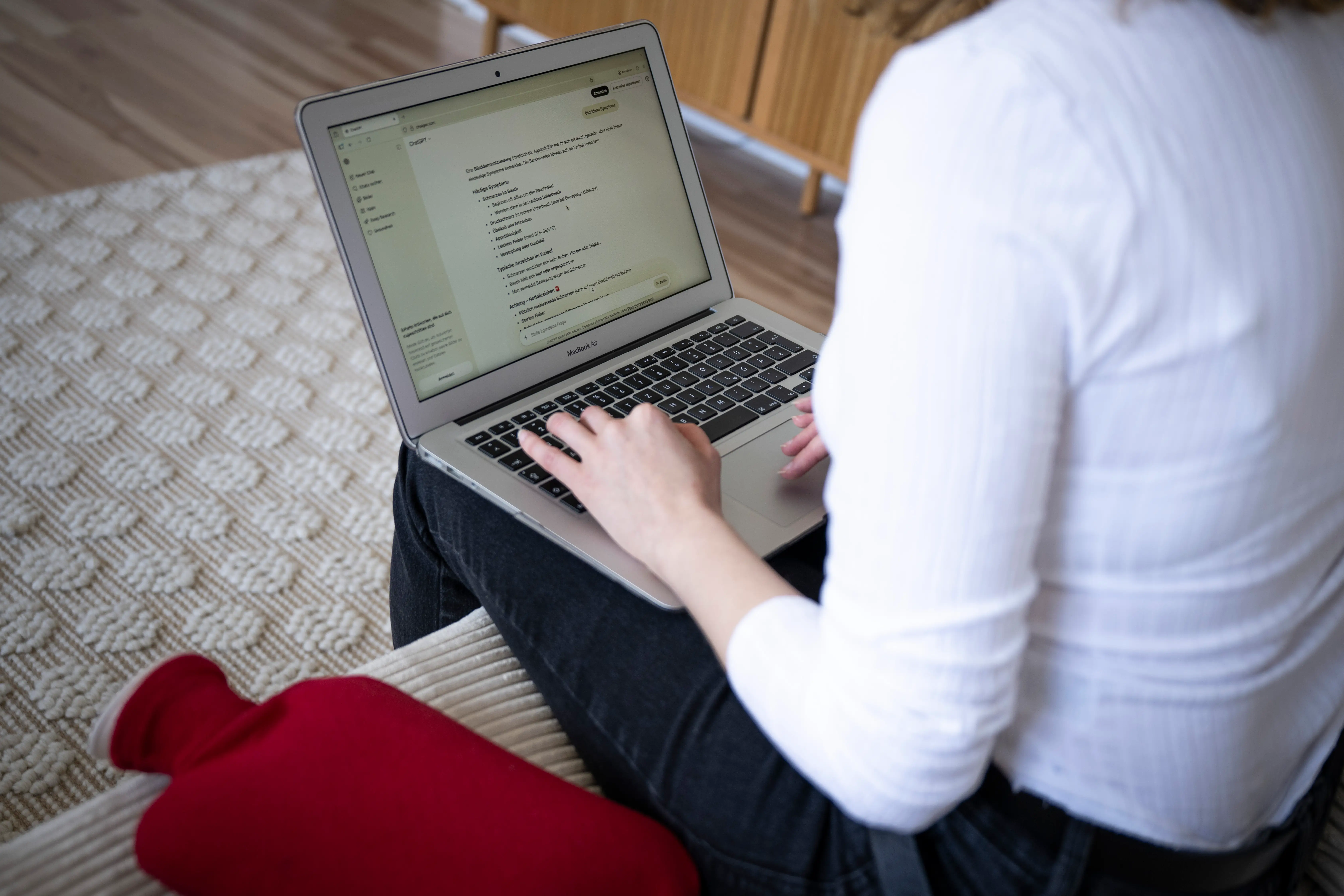 A person sits on a sofa with a laptop and searches the internet, including ChatGPT