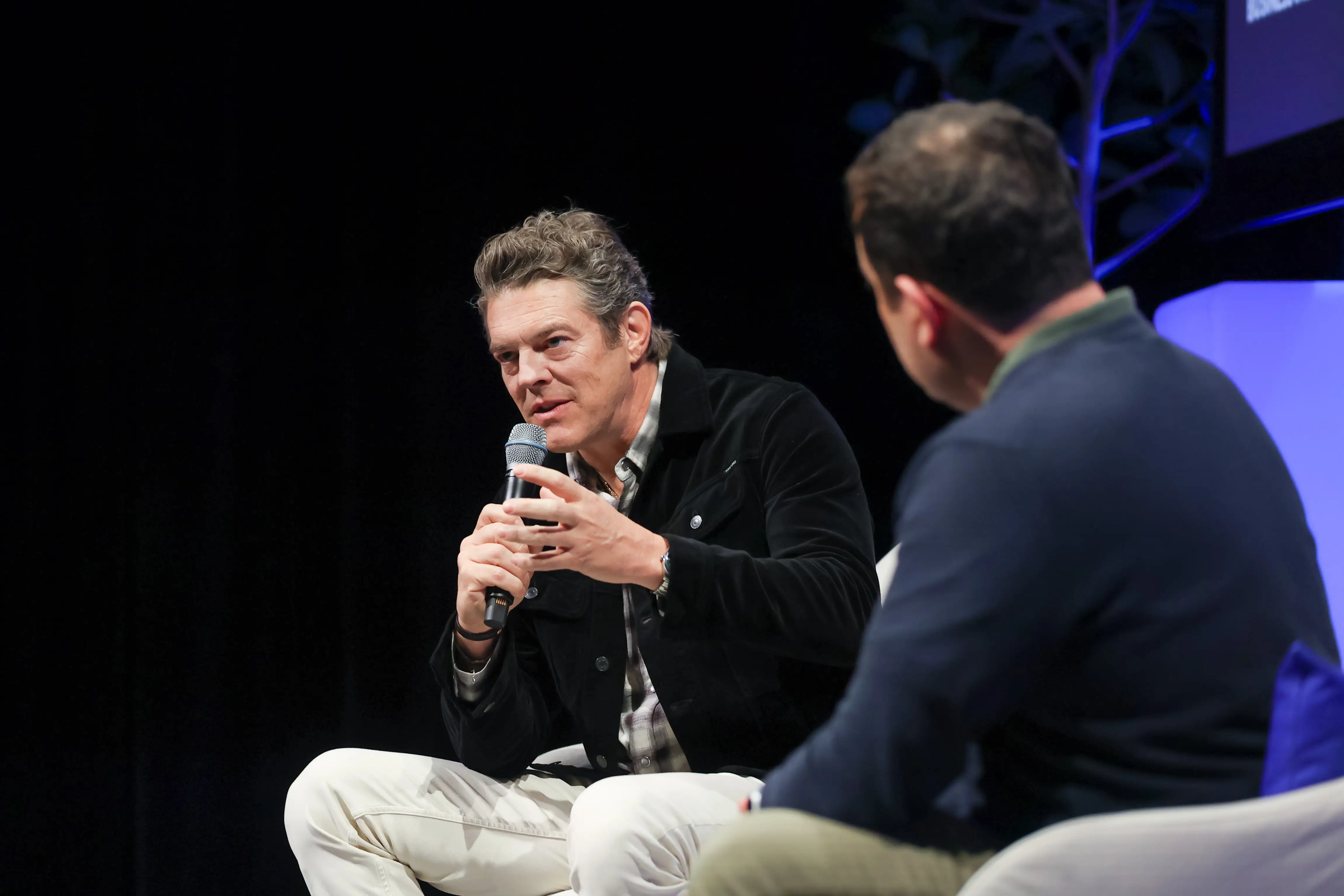 Jason Blum holding a microphone and speaking at an event