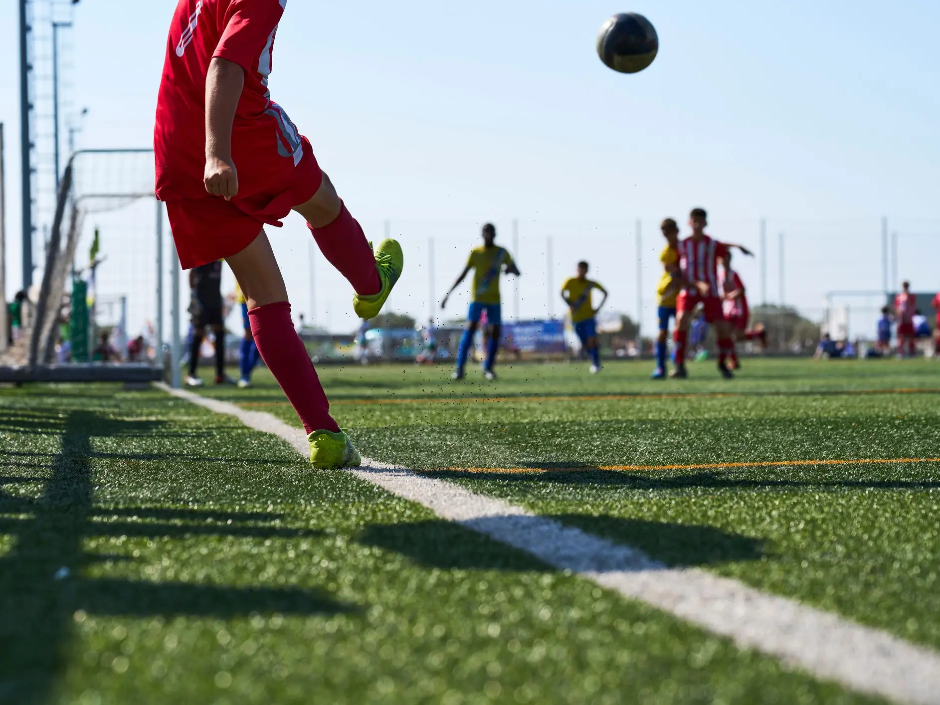 View of boy kicking soccer ball from corner to his team.