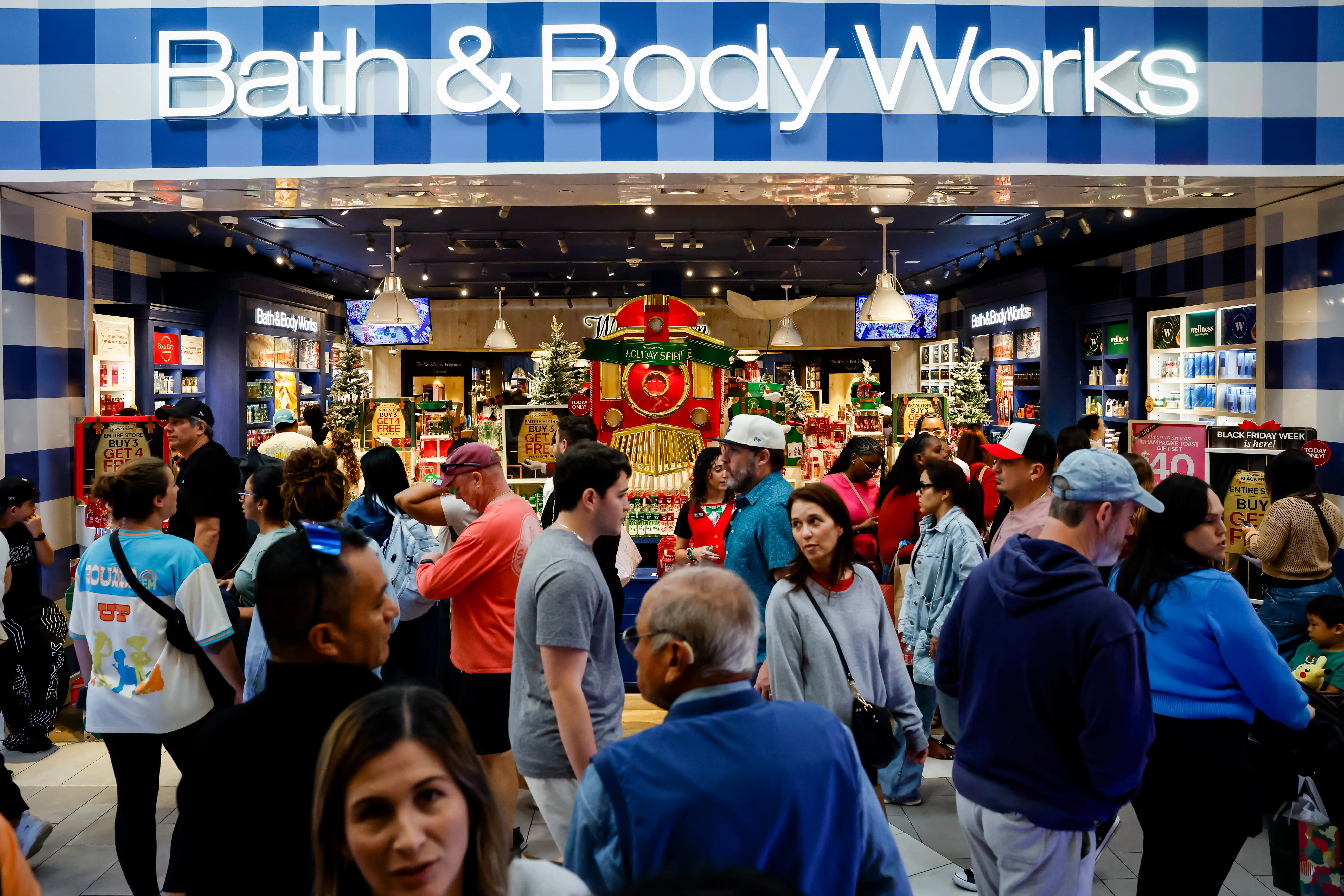 Shoppers walk outside of a Bath & Body Works store in a mall.