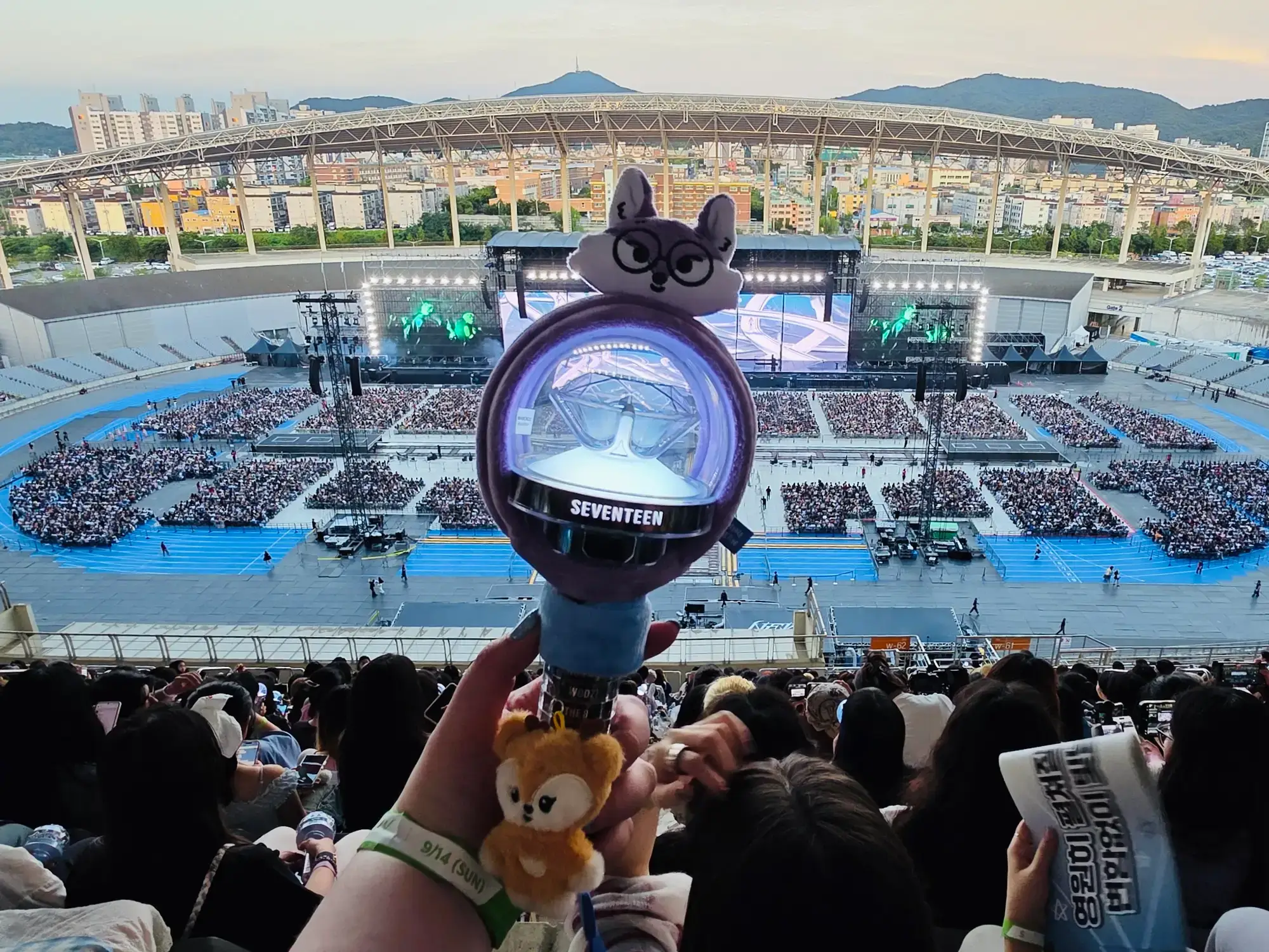 A view of a light stick with Seventeen's Seoul concert stage in the background.