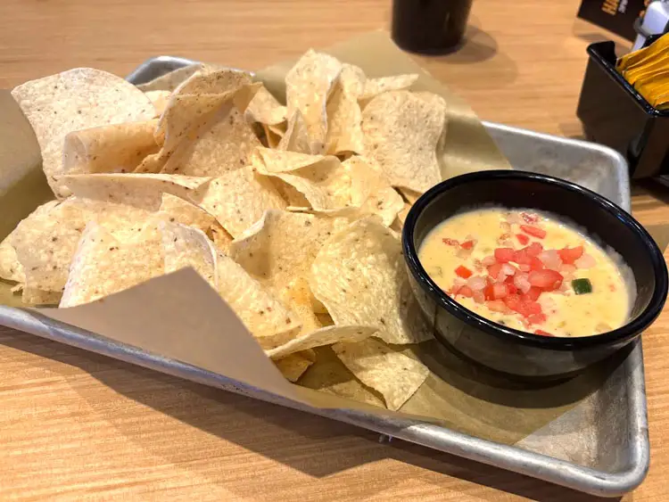 Chips and queso on a metal tray.