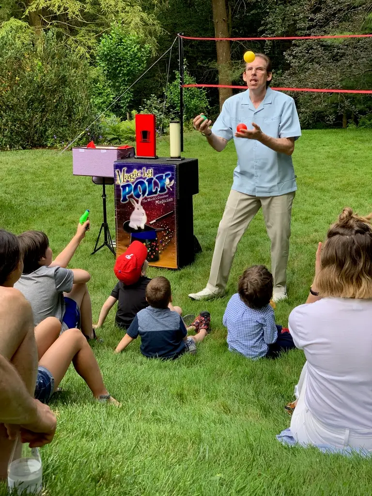 The author's family sitting on the grass at their family reunion watching a magic show.