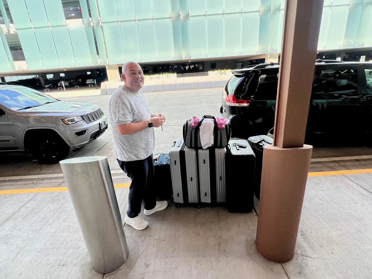 A man with a lot of luggage outside an airport.