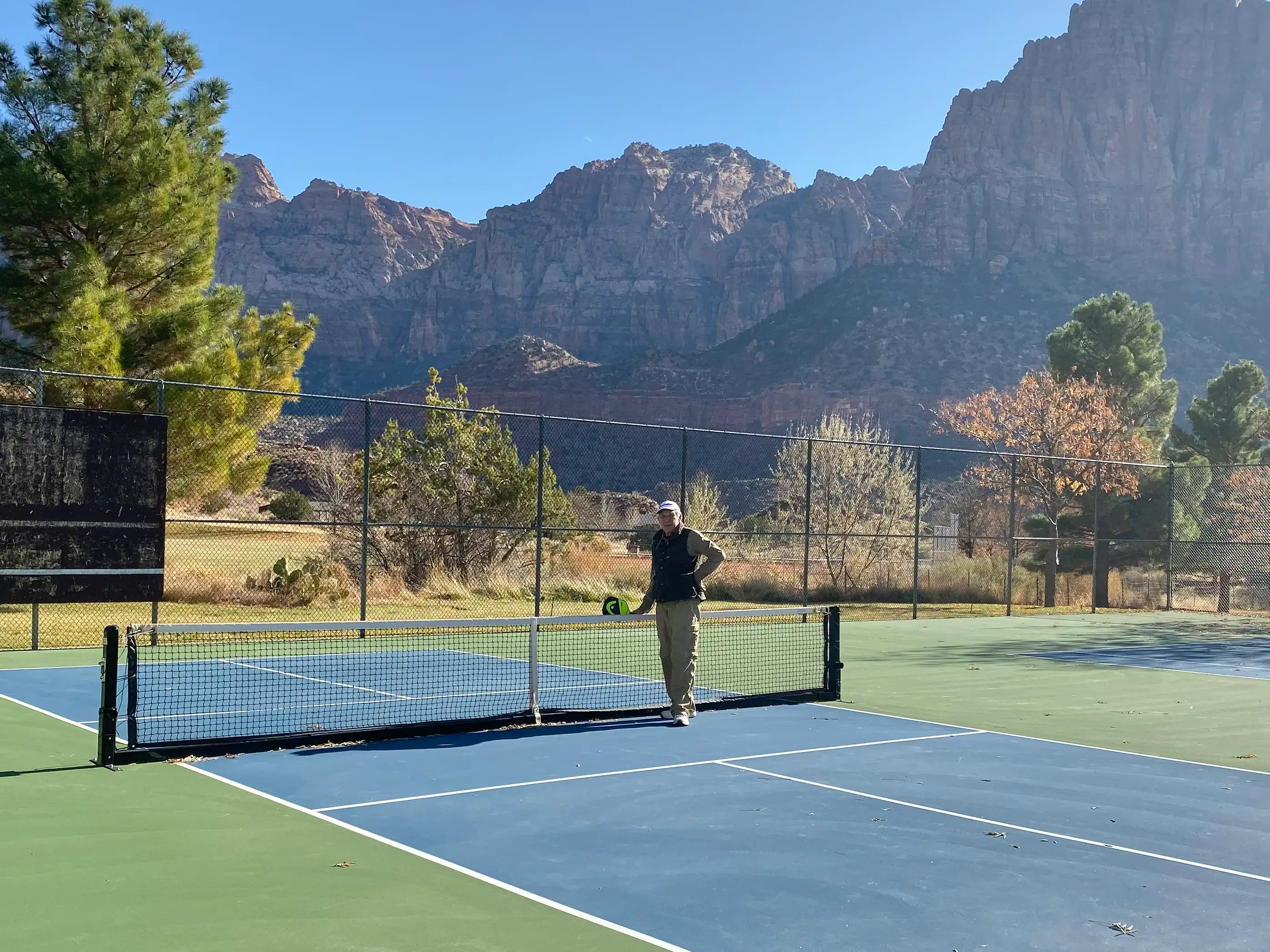 A man standing in the middle of a pickleball court.