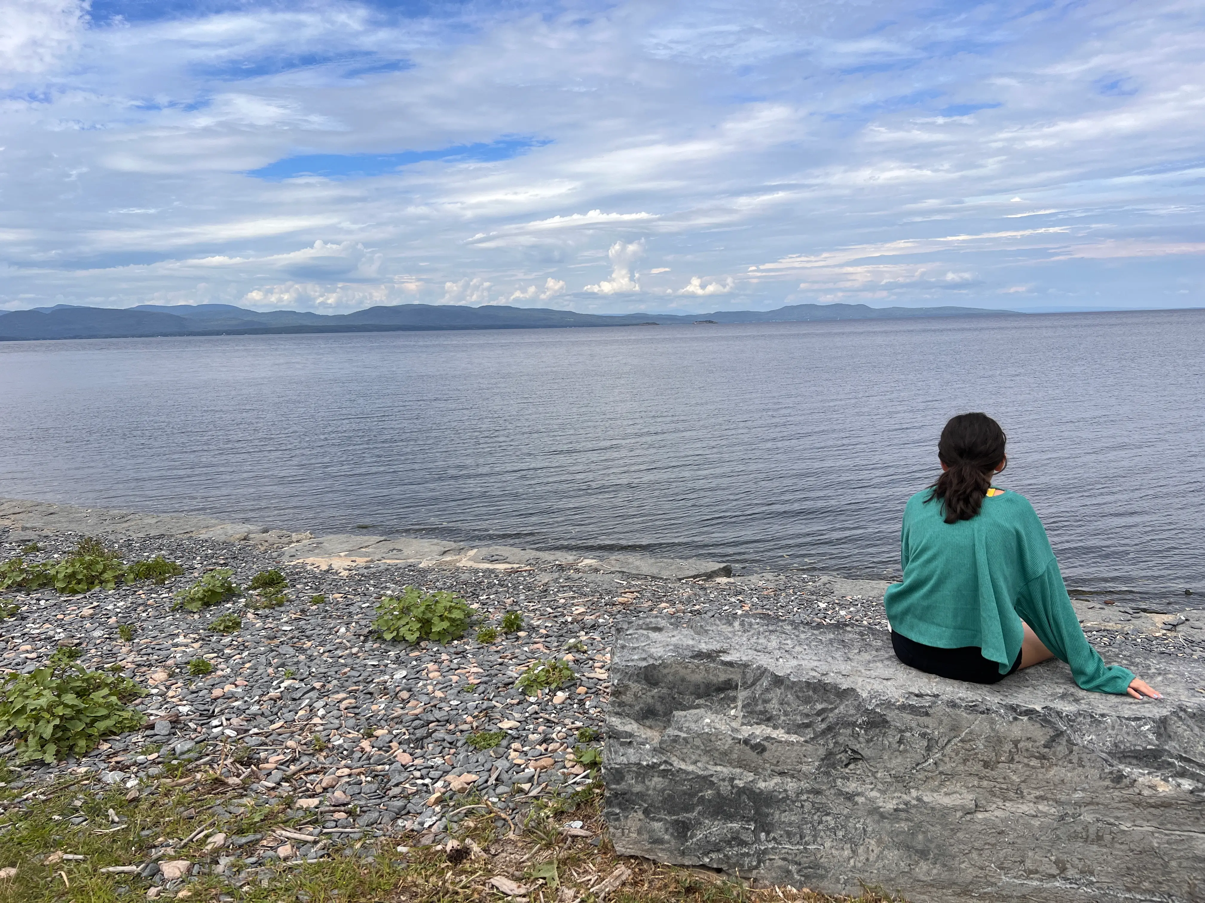 The author's daughter sits on the shore of a lake.