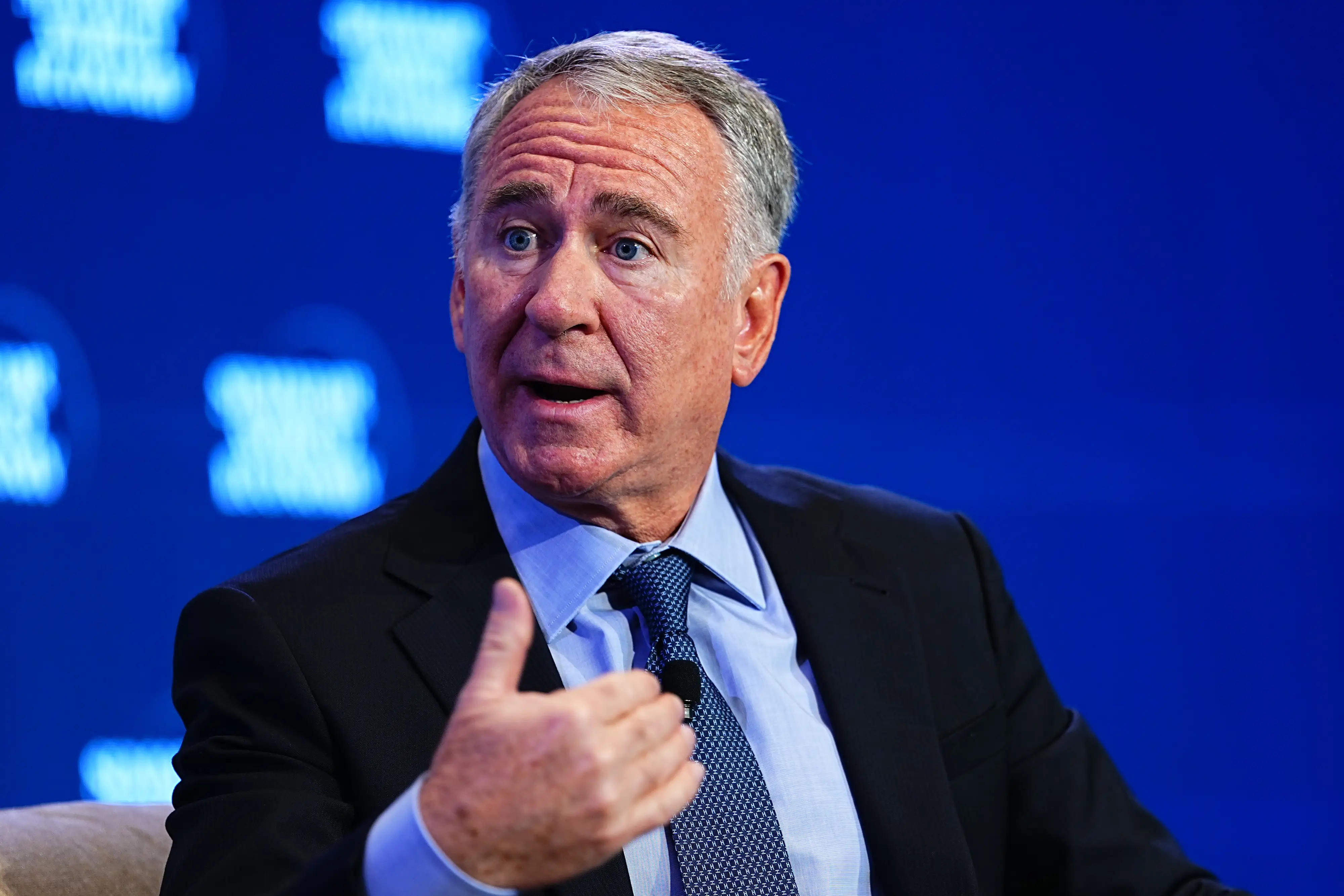 Ken Griffin speaking on stage in a black suit