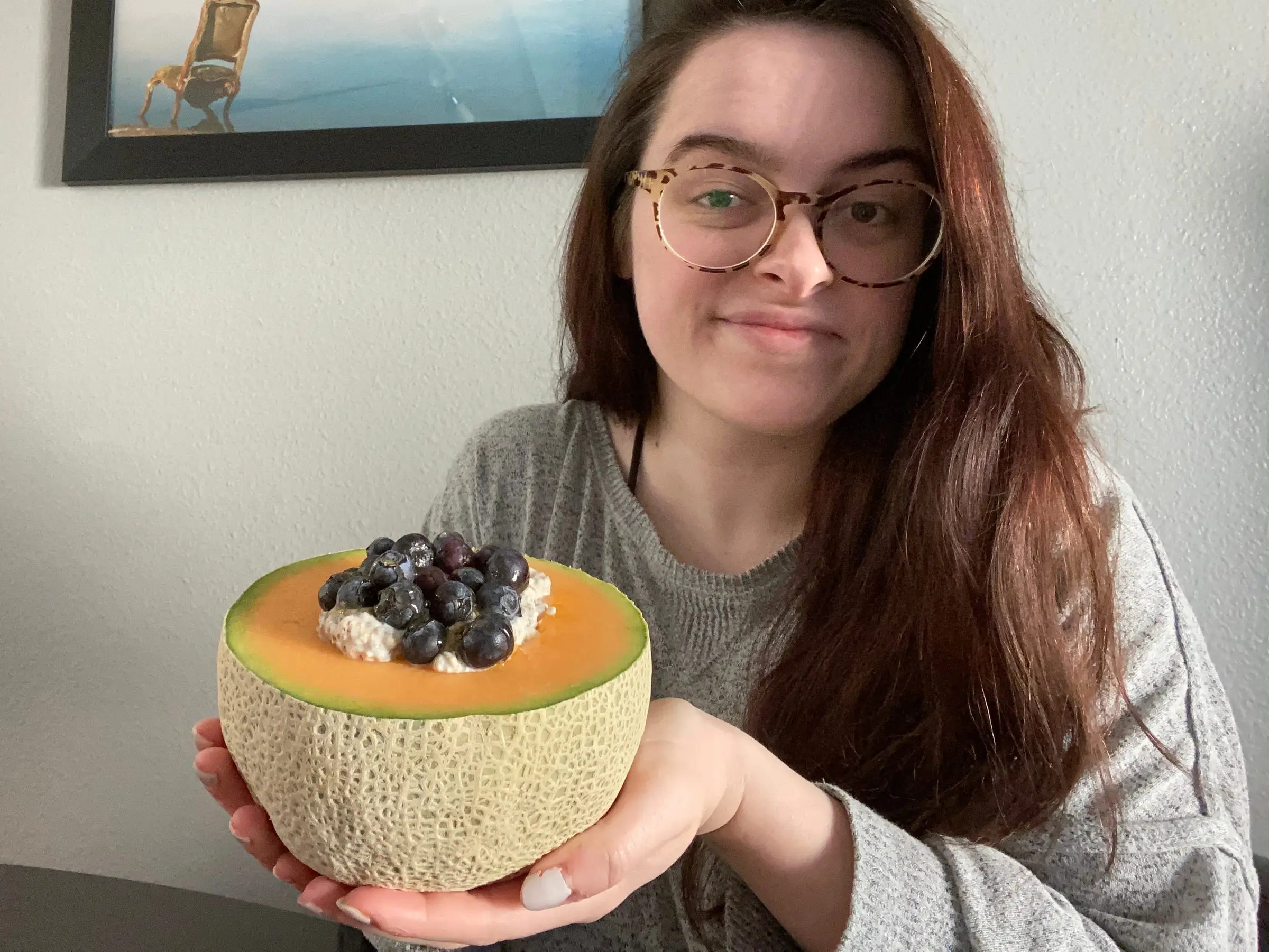 woman holding half of cantaloupe with oats, berries in it