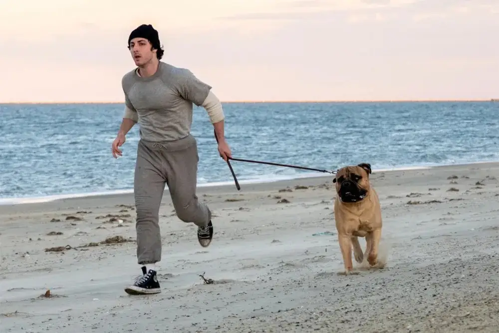 Anthony Ippolito running on a beach with a dog in I Play Rocky