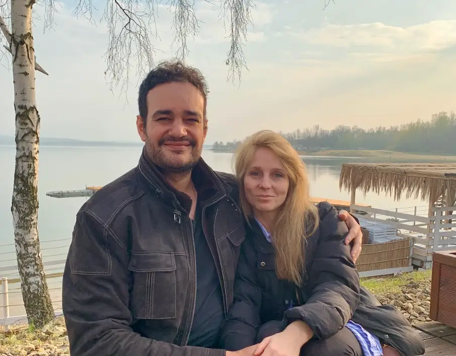 The writer and her husband sitting on a bench in front of the water.