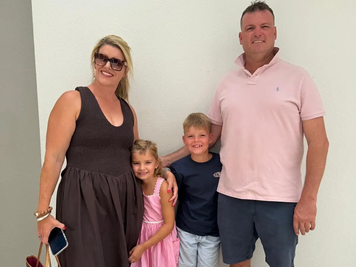 A family of four posing in front of a white wall.