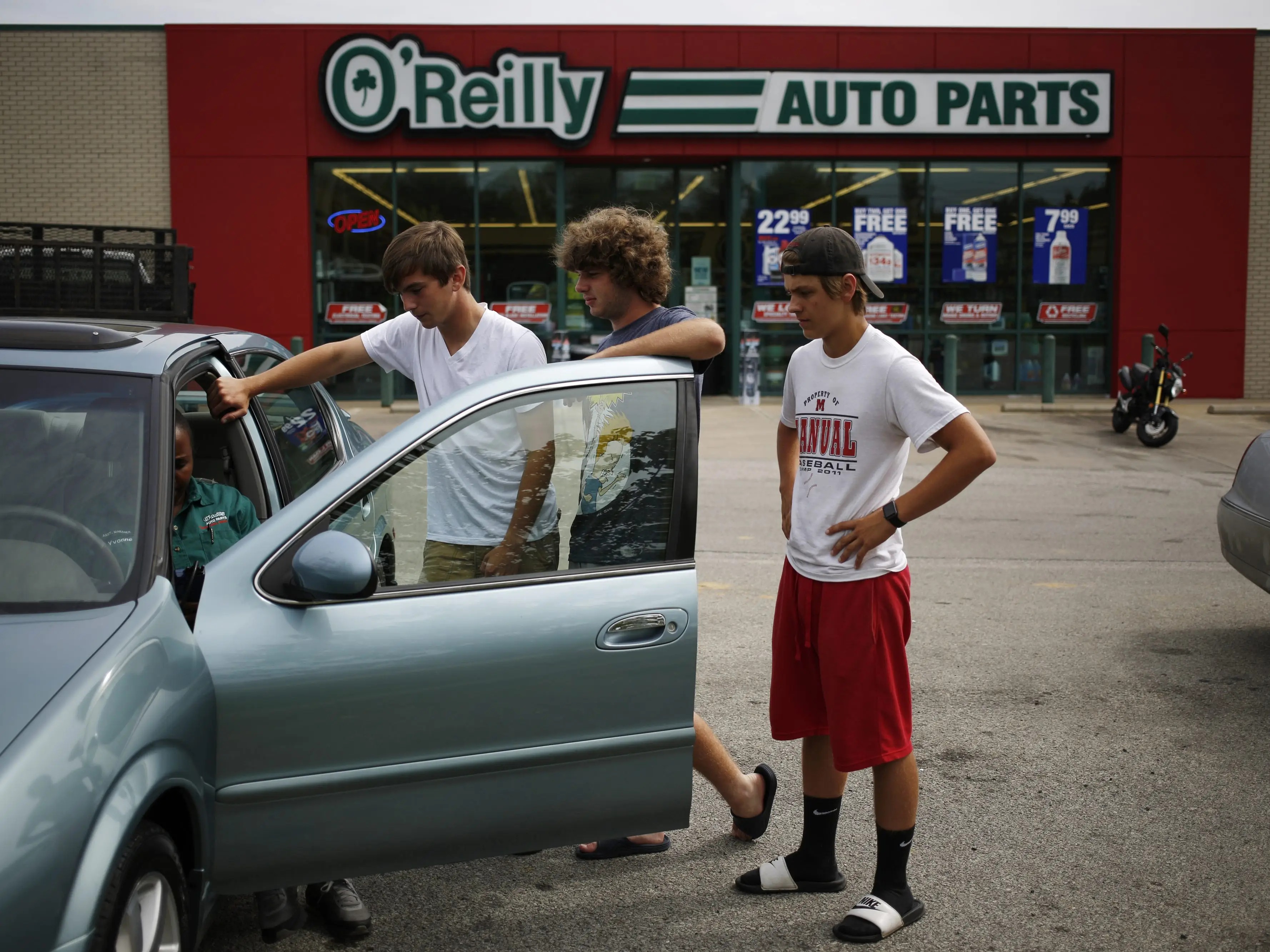 Customers watch as an employee investigates a check engine light on their vehicle outside an O'Reilly Automotive Inc. auto parts store in Louisville, Kentucky.