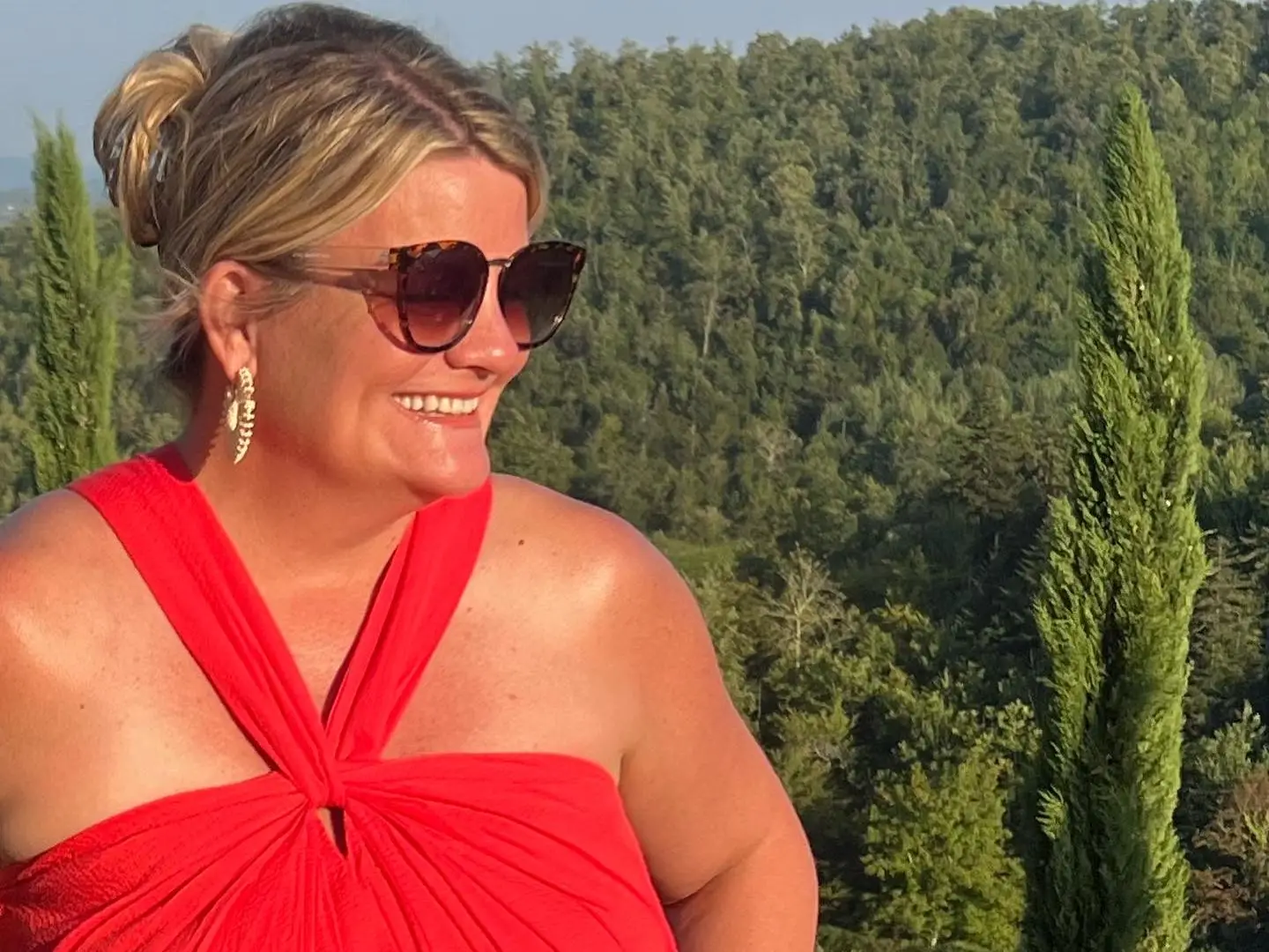 A woman in a red halter-neck dress, wearing sunglasses in Italy.