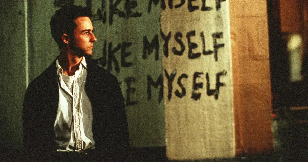 Edward Norton standing in front of wall with writing on it in Fight Club movie