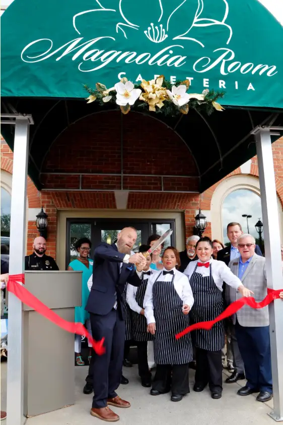 Louis Squires cutting red ribbon for opening of Magnolia Room.