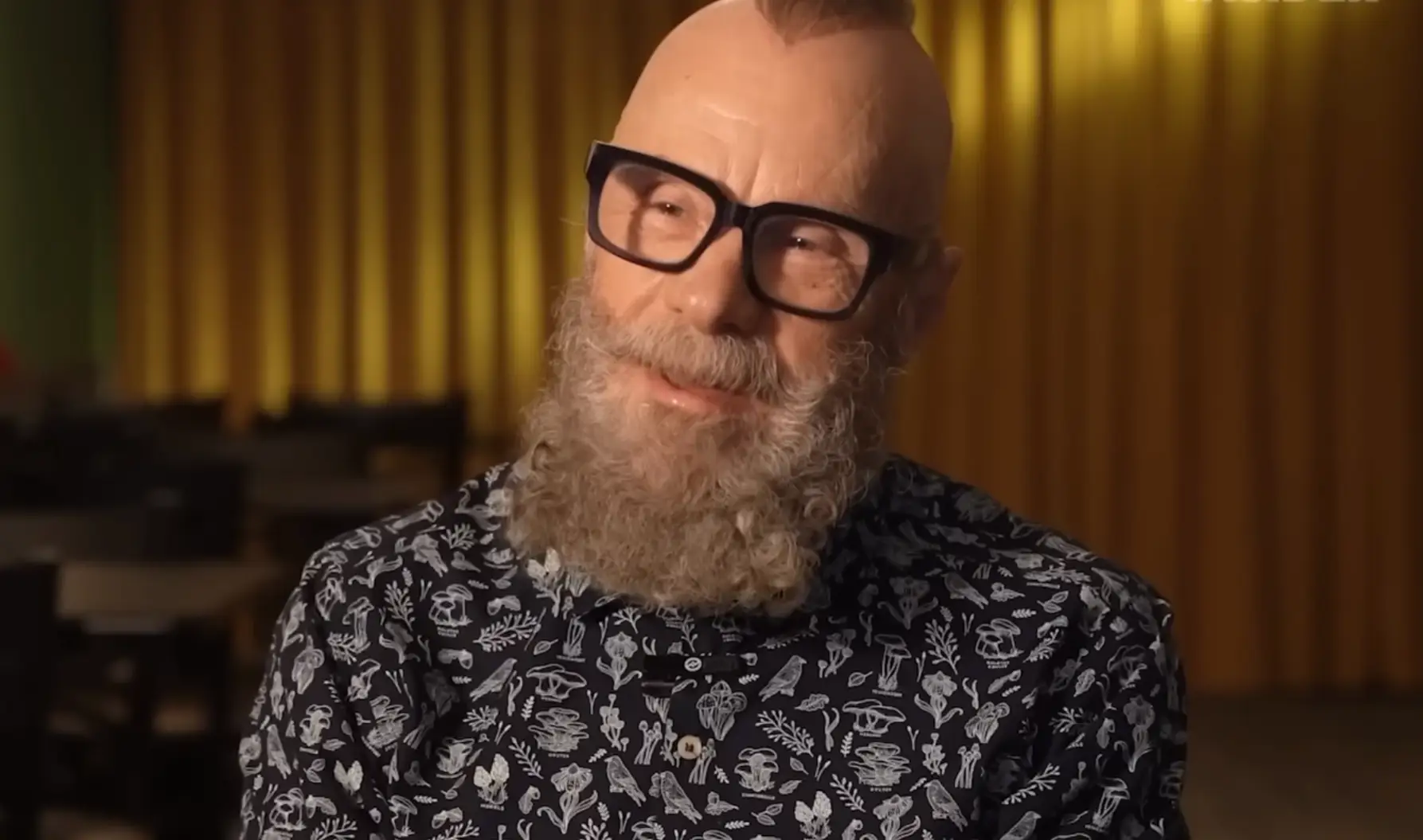 Image of Louis Squires in black print shirt and black glasses.