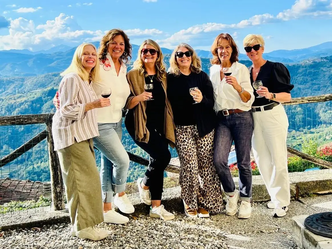 A group of six women standing amid mountains in Italy.