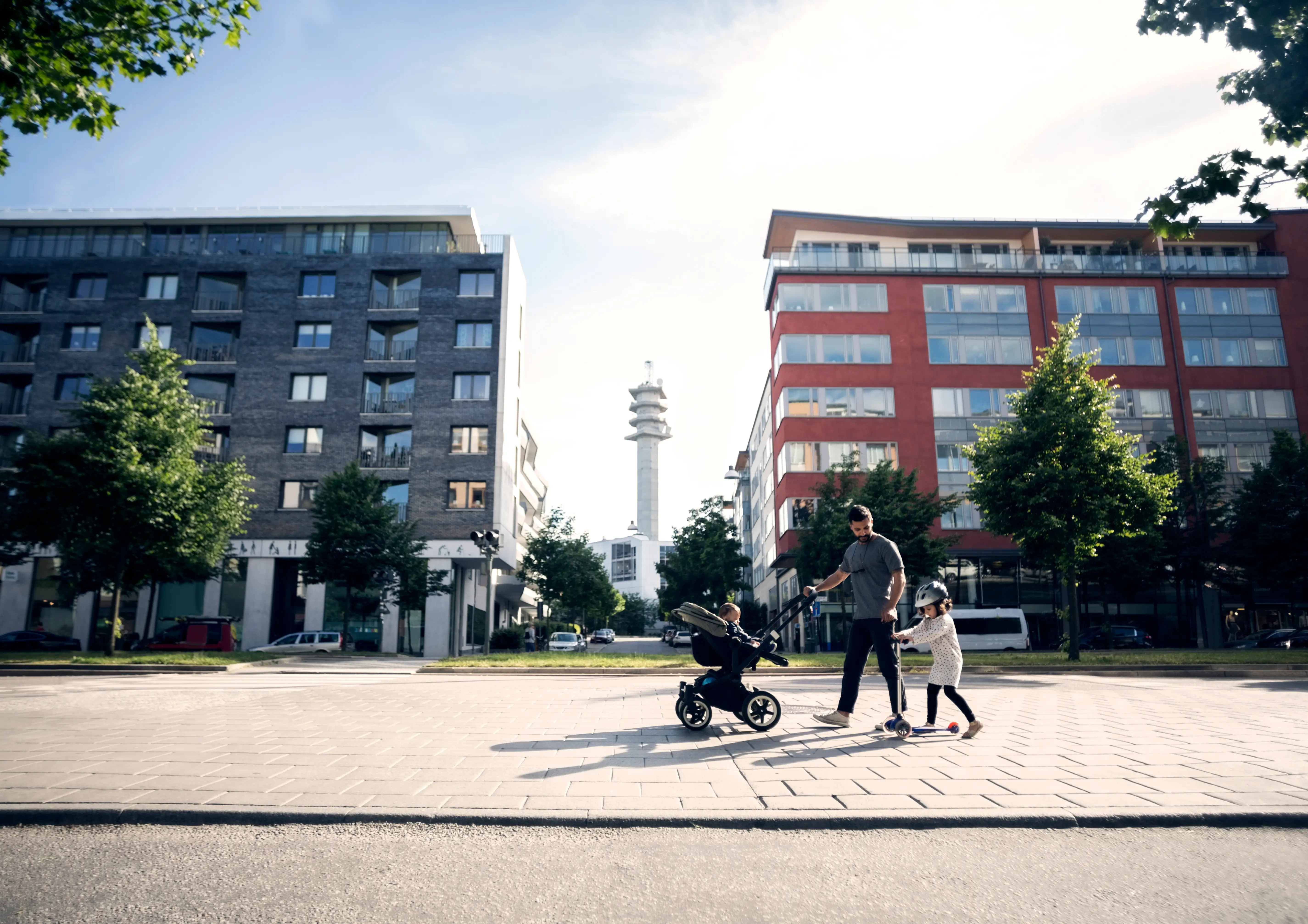 parent pushing stroller next to kid on scooter