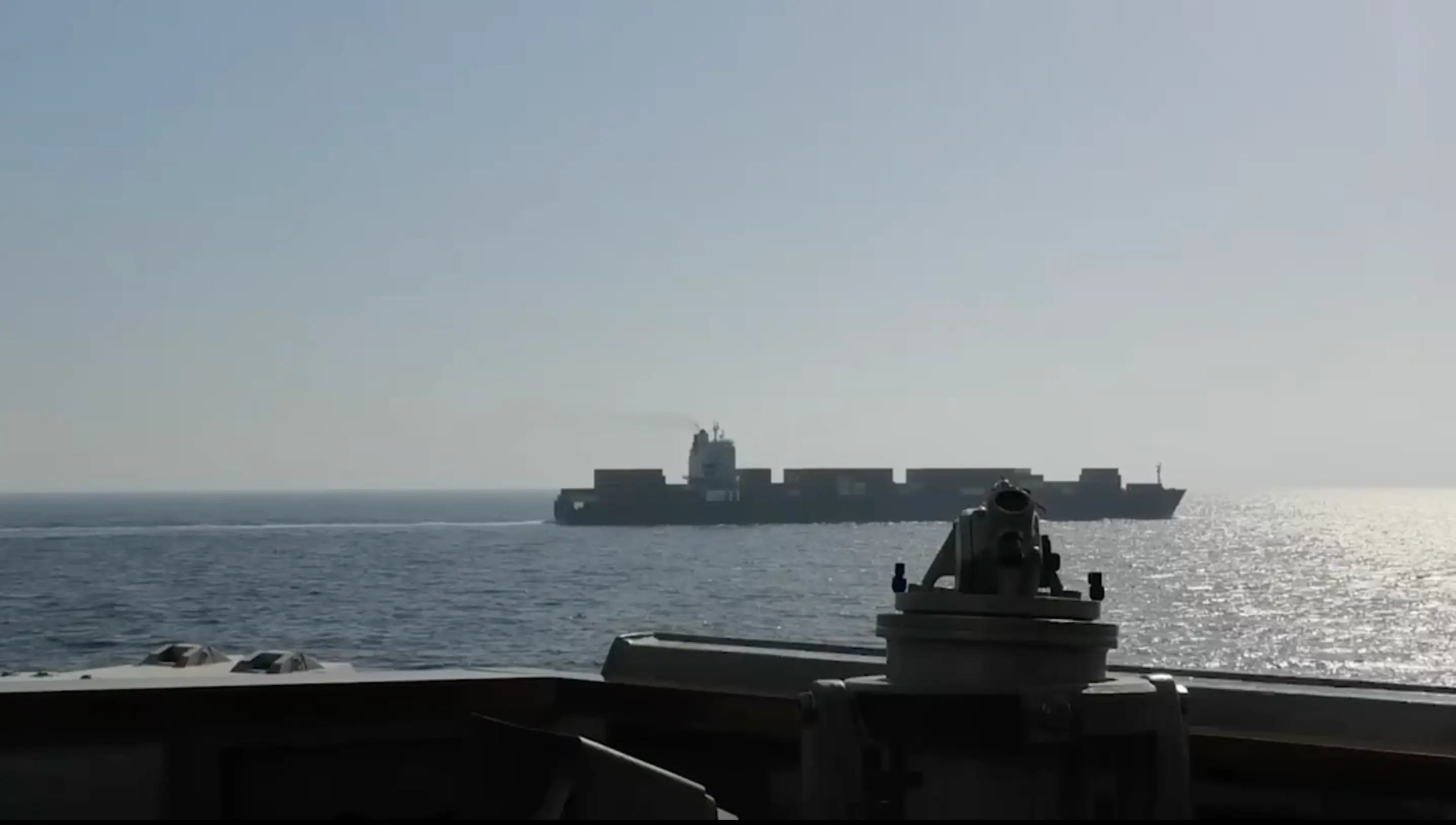 A screenshot of a video aboard a US Navy ship looking out towards an Iranian cargo vessel sailing in the water.