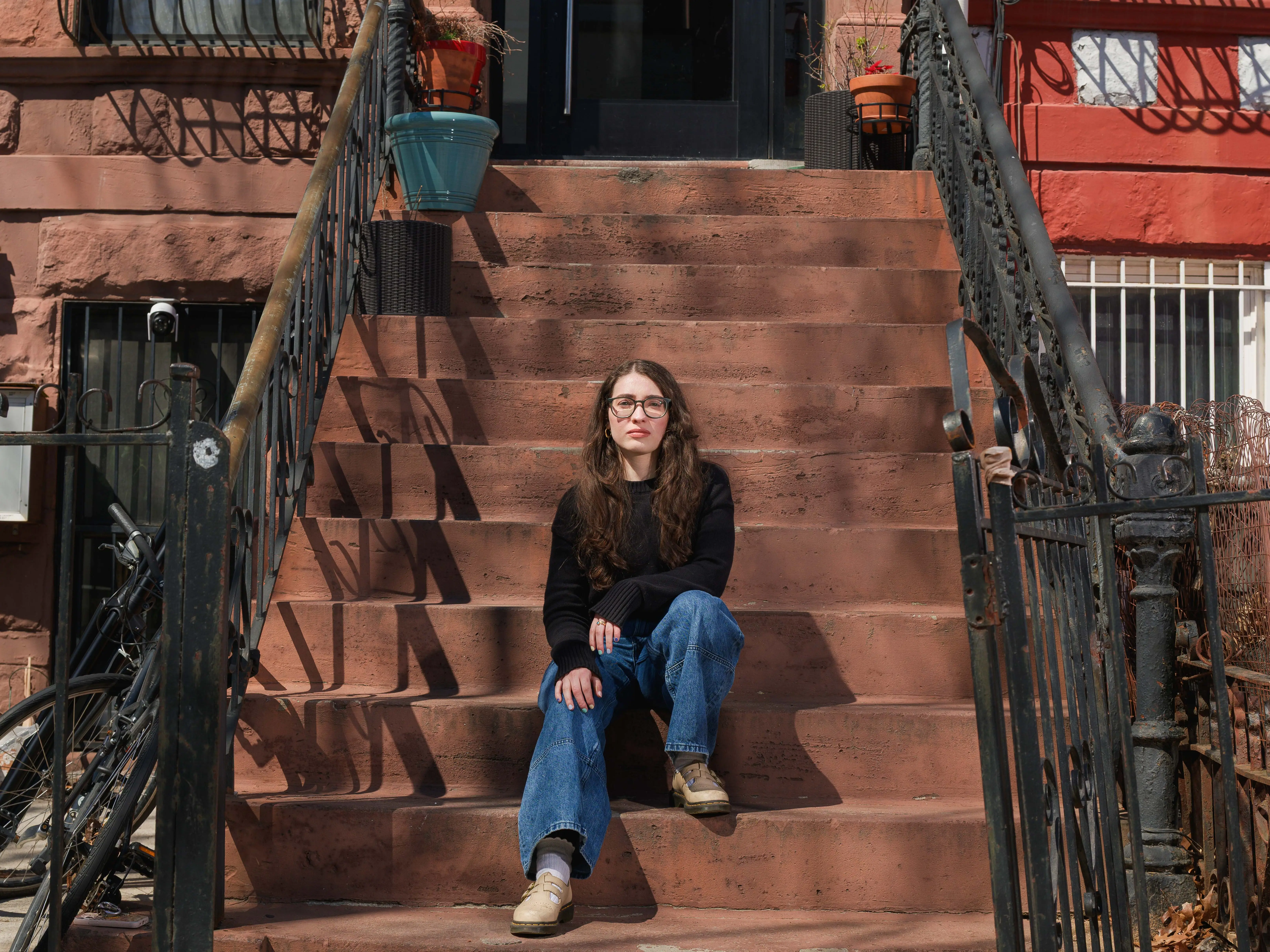the author is sitting on the outdoor steps to her NYC apartment