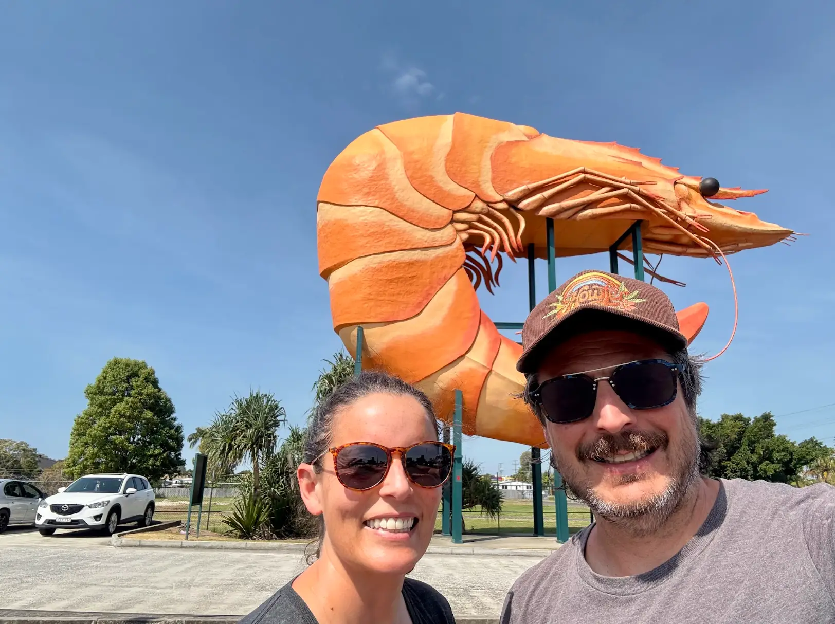 The writer and his wife standing in front of a giant prawn sculpture in Australia.