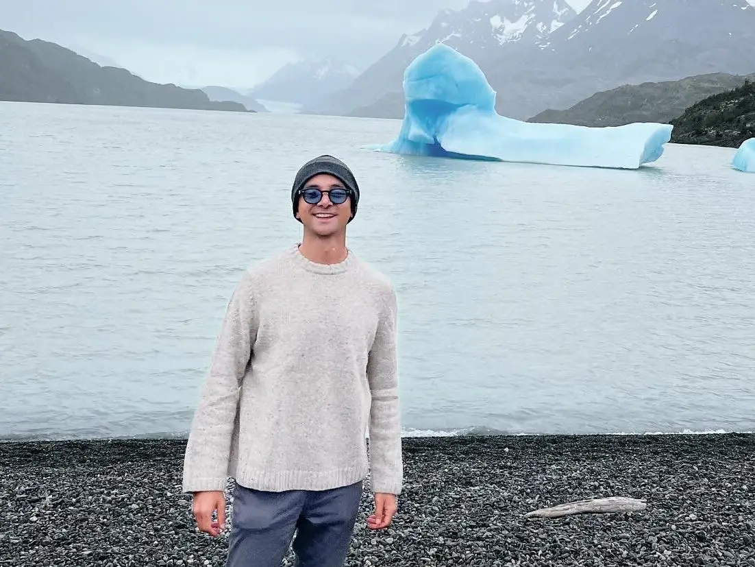 Santiago Barraza Lopez standing on the edge of a waterline with glaciers in the background