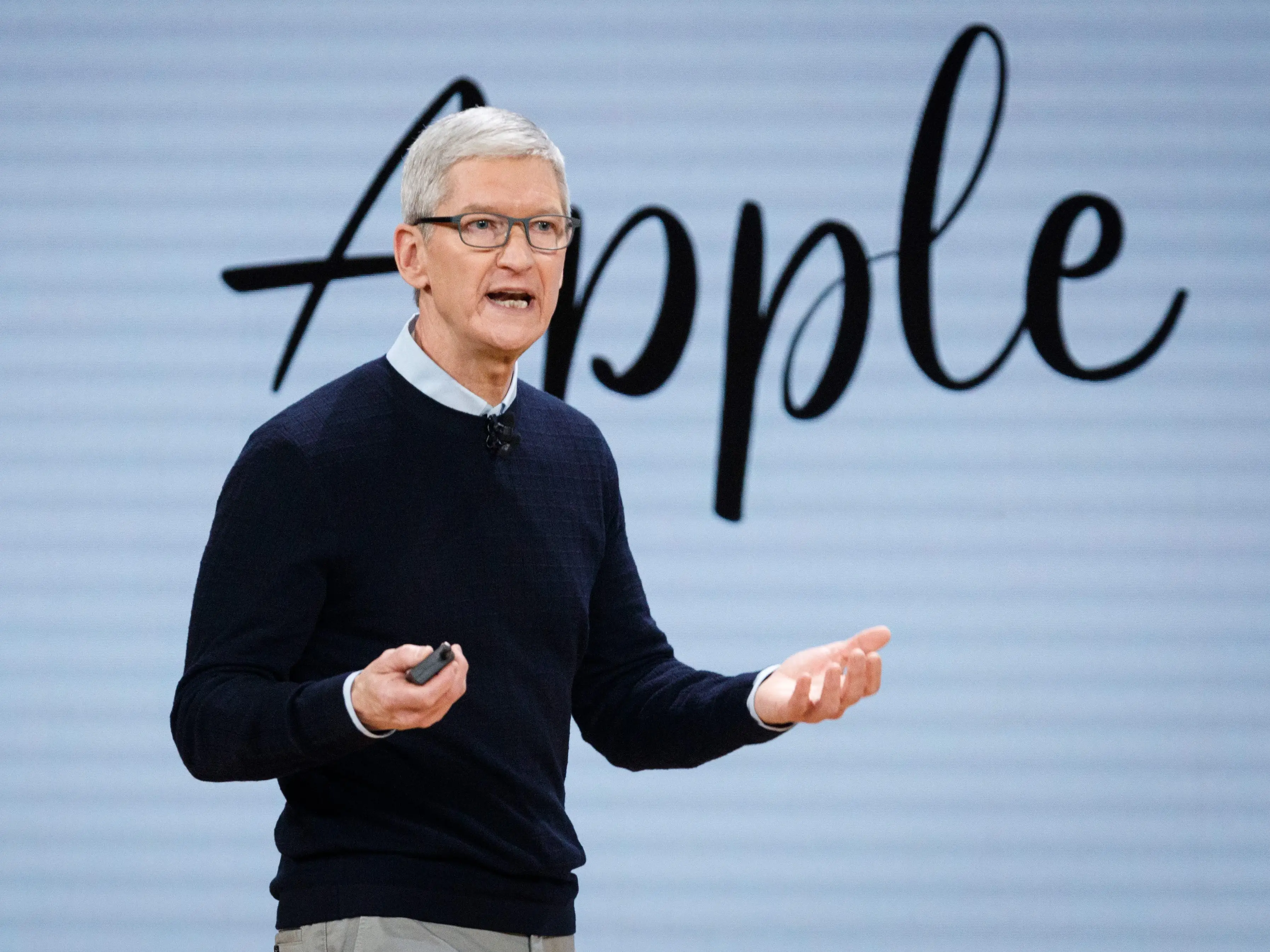 Tim Cook speaking during a presentation in front of cursive 