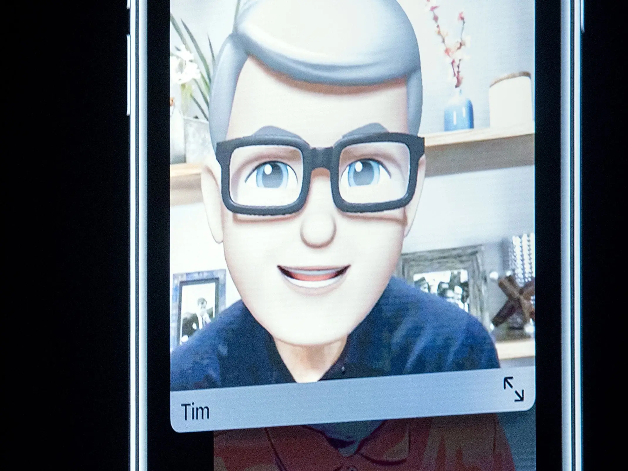 A Tim Cook Memoji displays on a phone screen during a presentation.