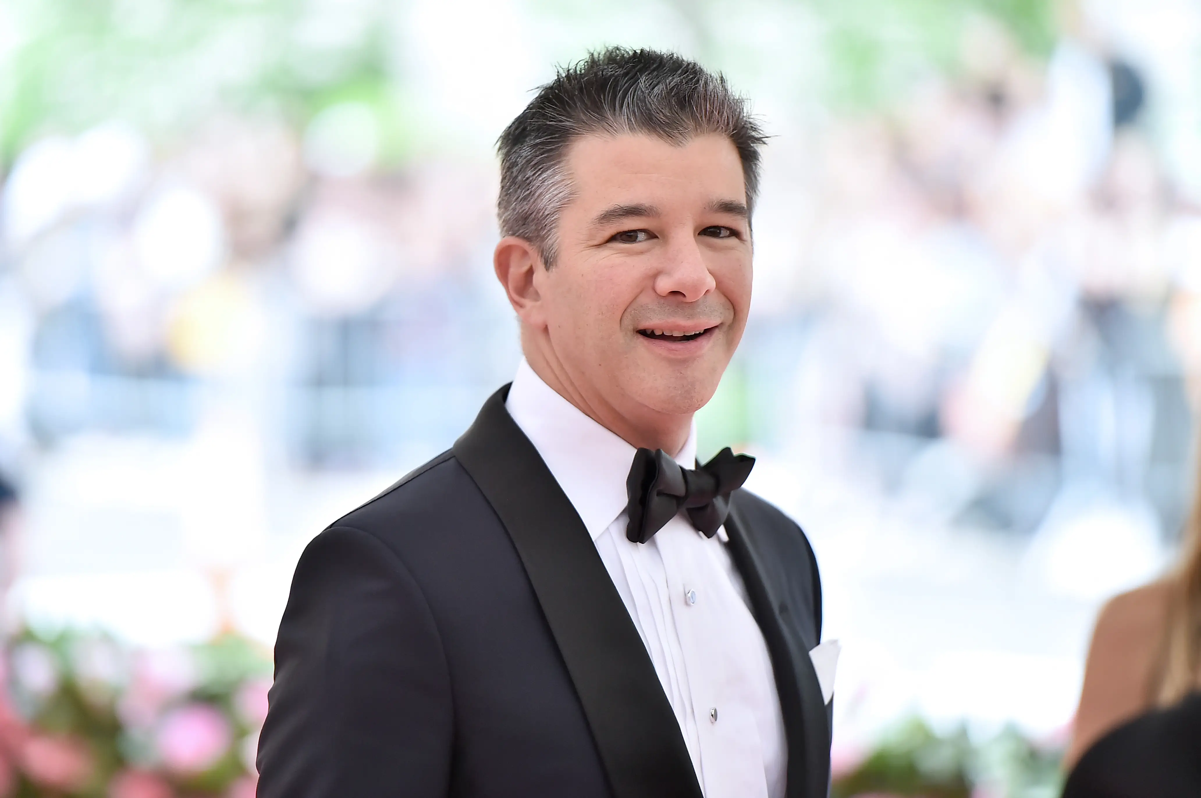Travis Kalanick wears a black and white suit with a bowtie.